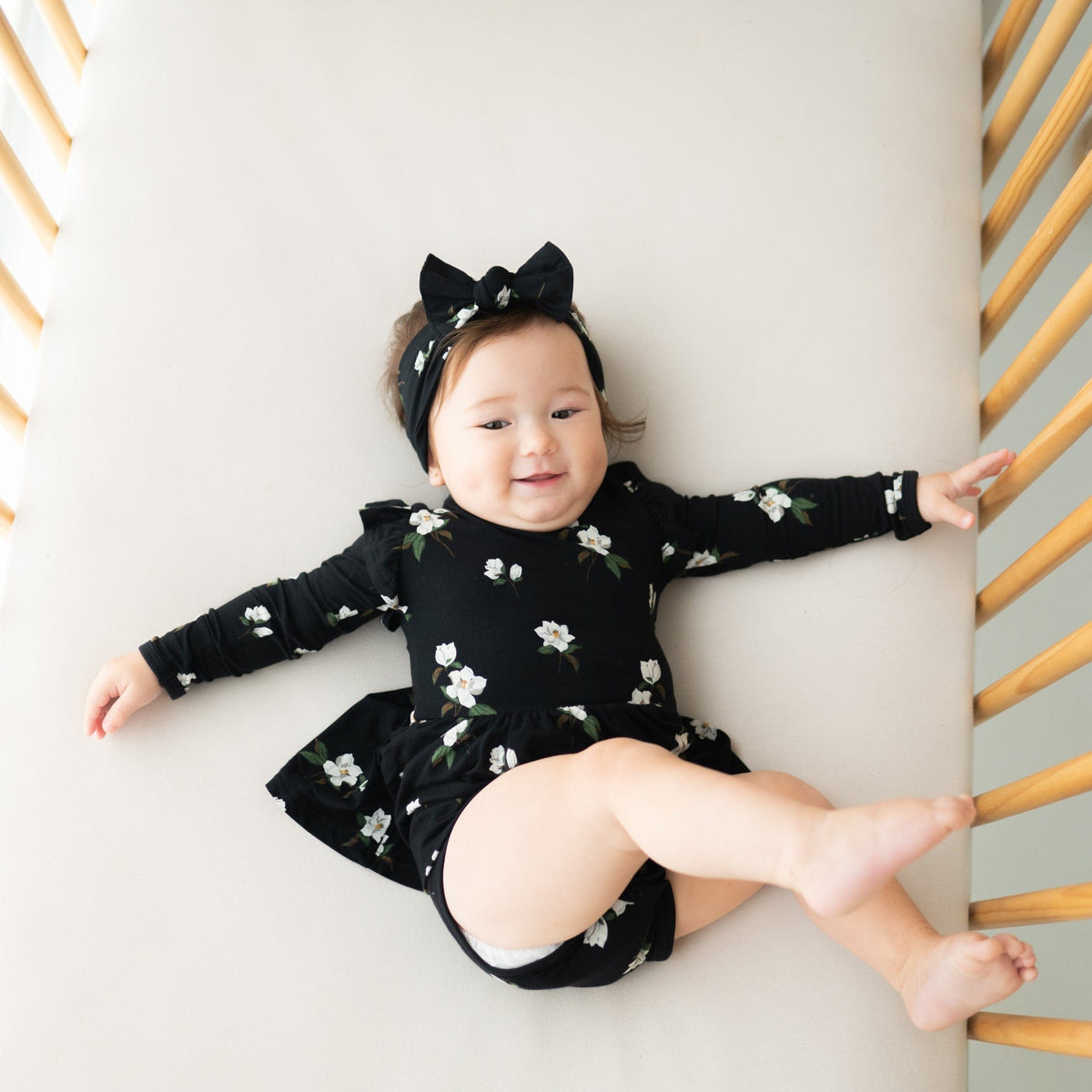 Baby wearing Kyte Baby Long Sleeve infant Twirl Bodysuit Dress in Small Midnight Magnolia