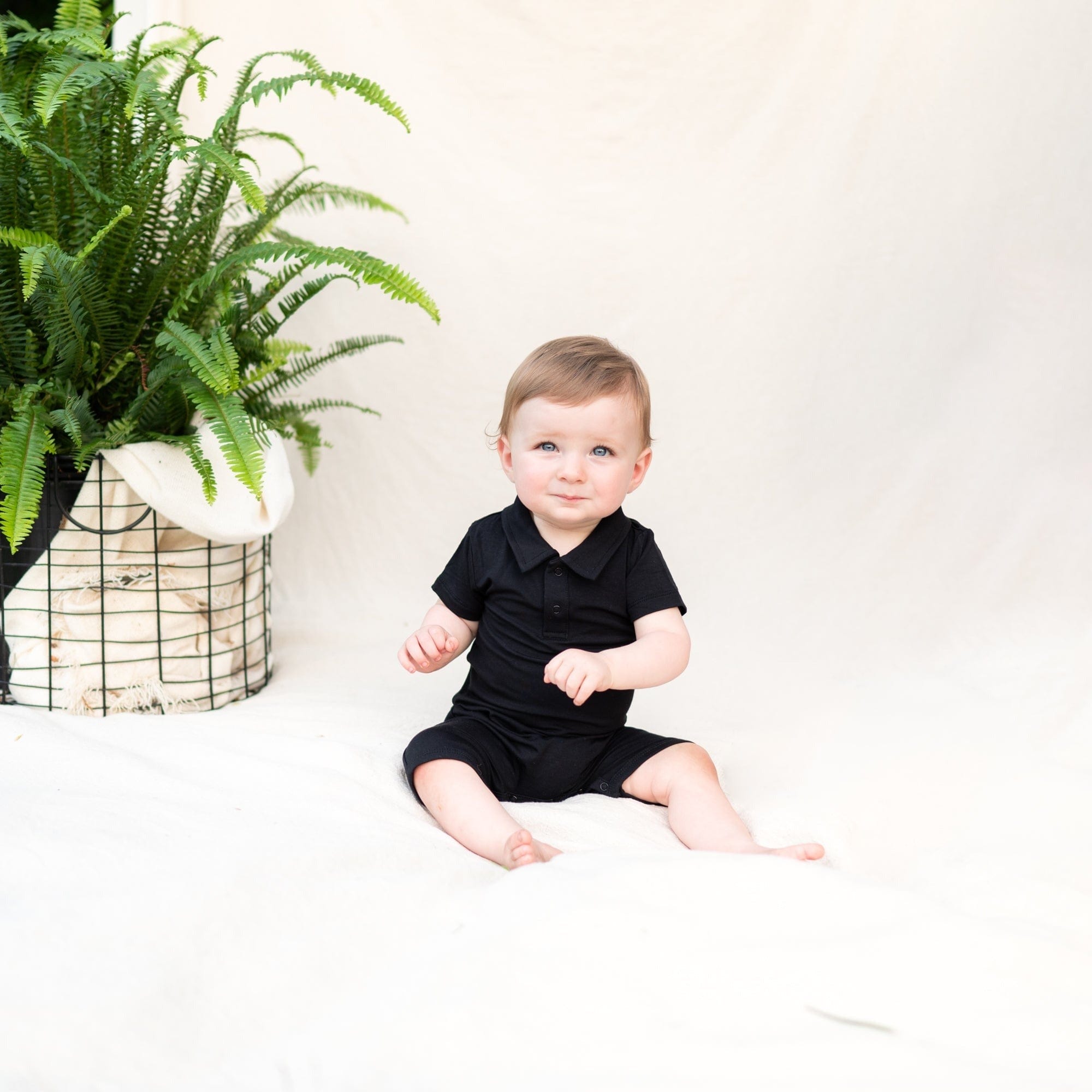 Infant wearing Kyte Baby Polo Shortall in Midnight