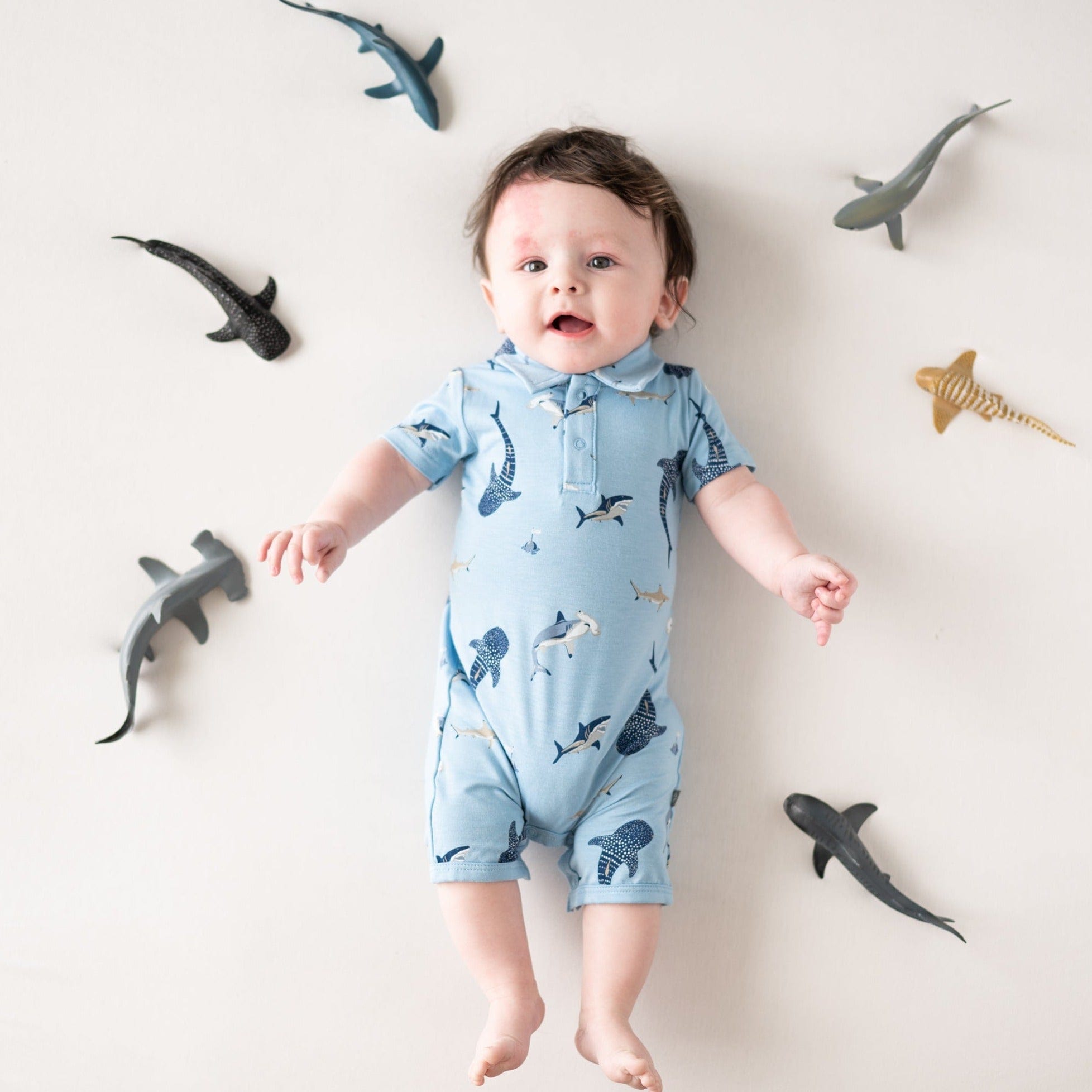 Infant wearing Kyte Baby Polo Shortall in Stream Shark