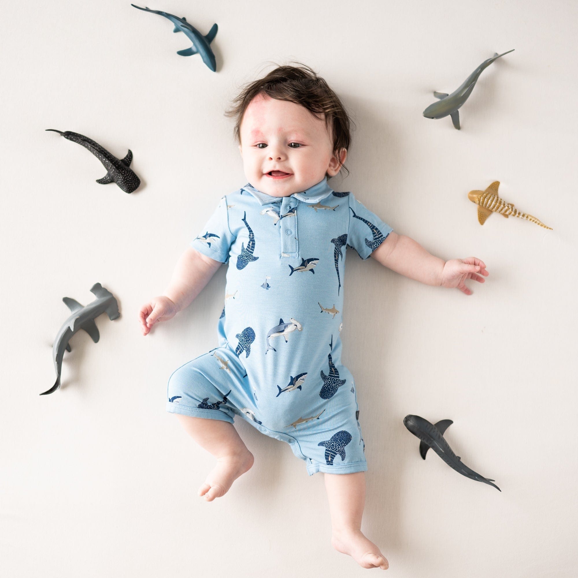 Infant wearing Kyte Baby bamboo Polo collar Shortall in Stream Shark
