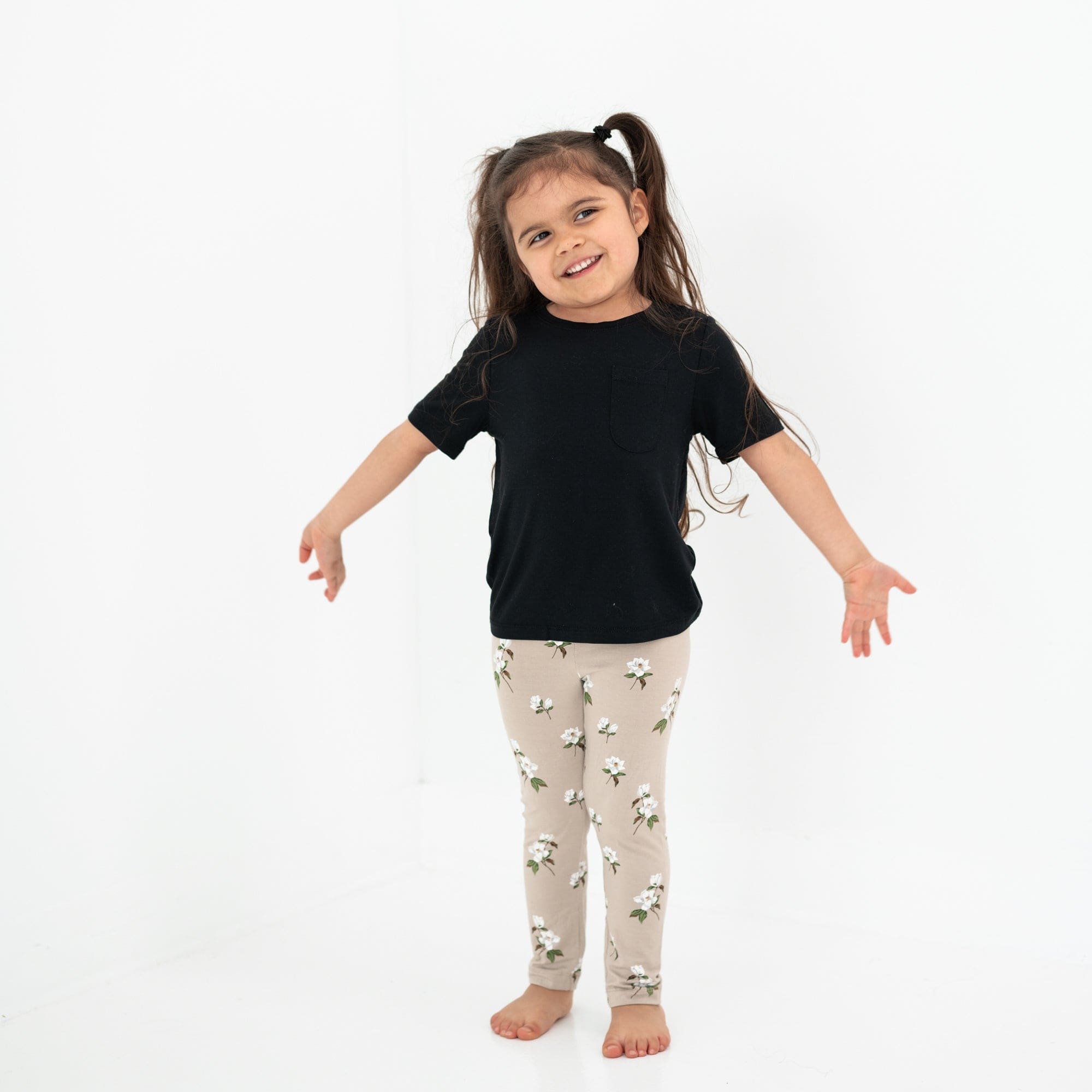 Child standing in a white room with arms spread open while wearing a Short Sleeve Toddler Unisex Tee in Midnight