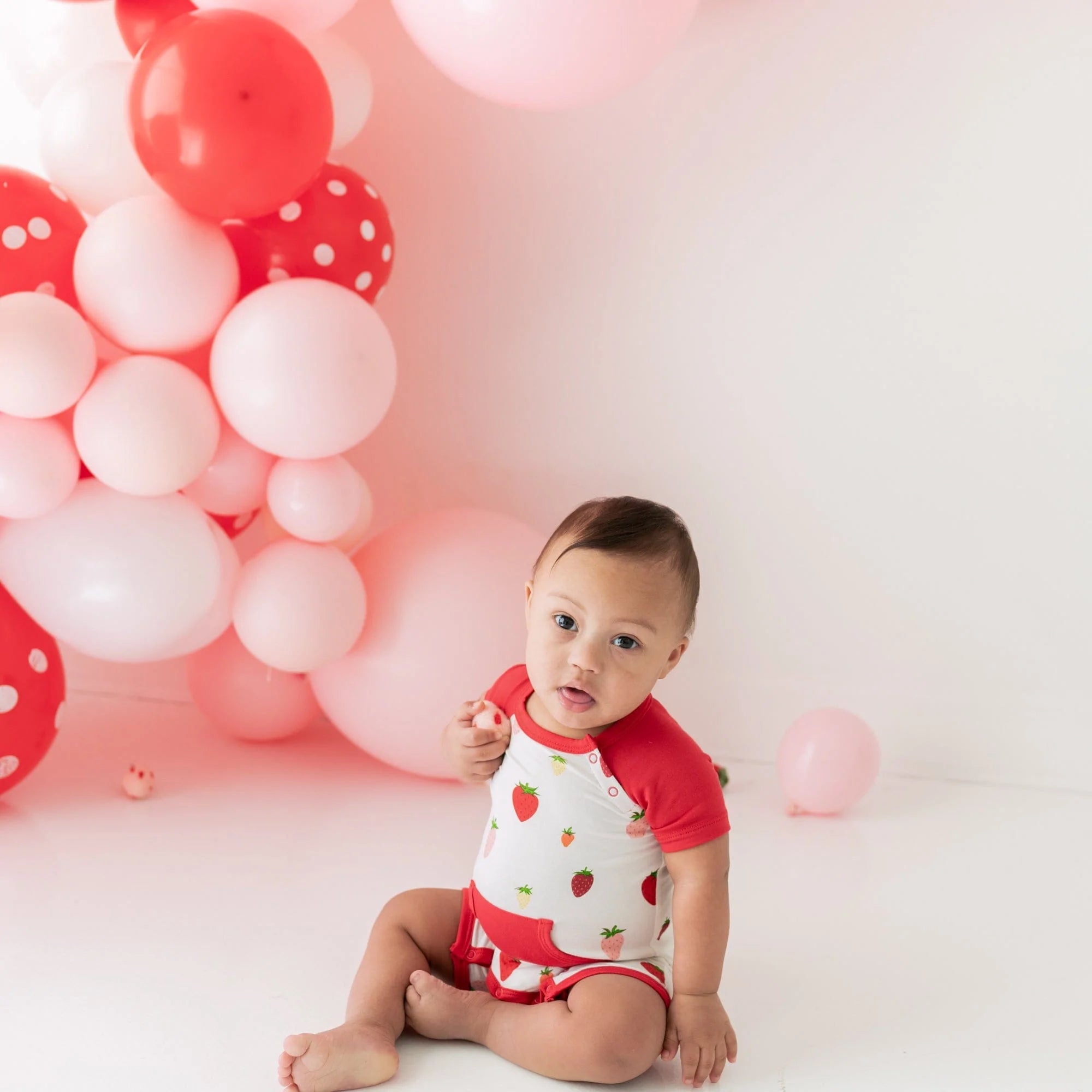 Infant wearing Kyte Baby Shortall in Strawberry with pocket