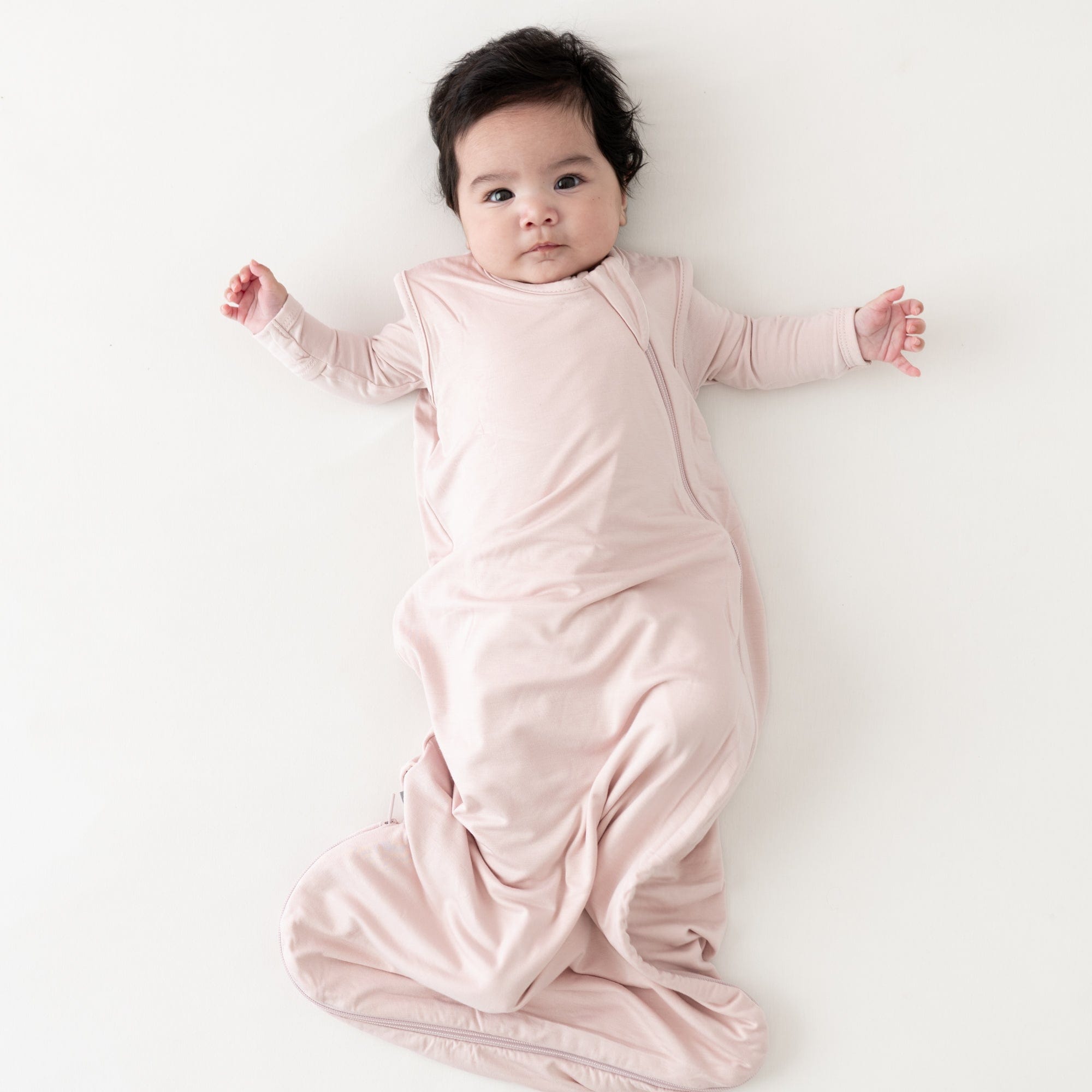 Baby wearing Kyte Baby Sleep Bag in Blush TOG 0.5