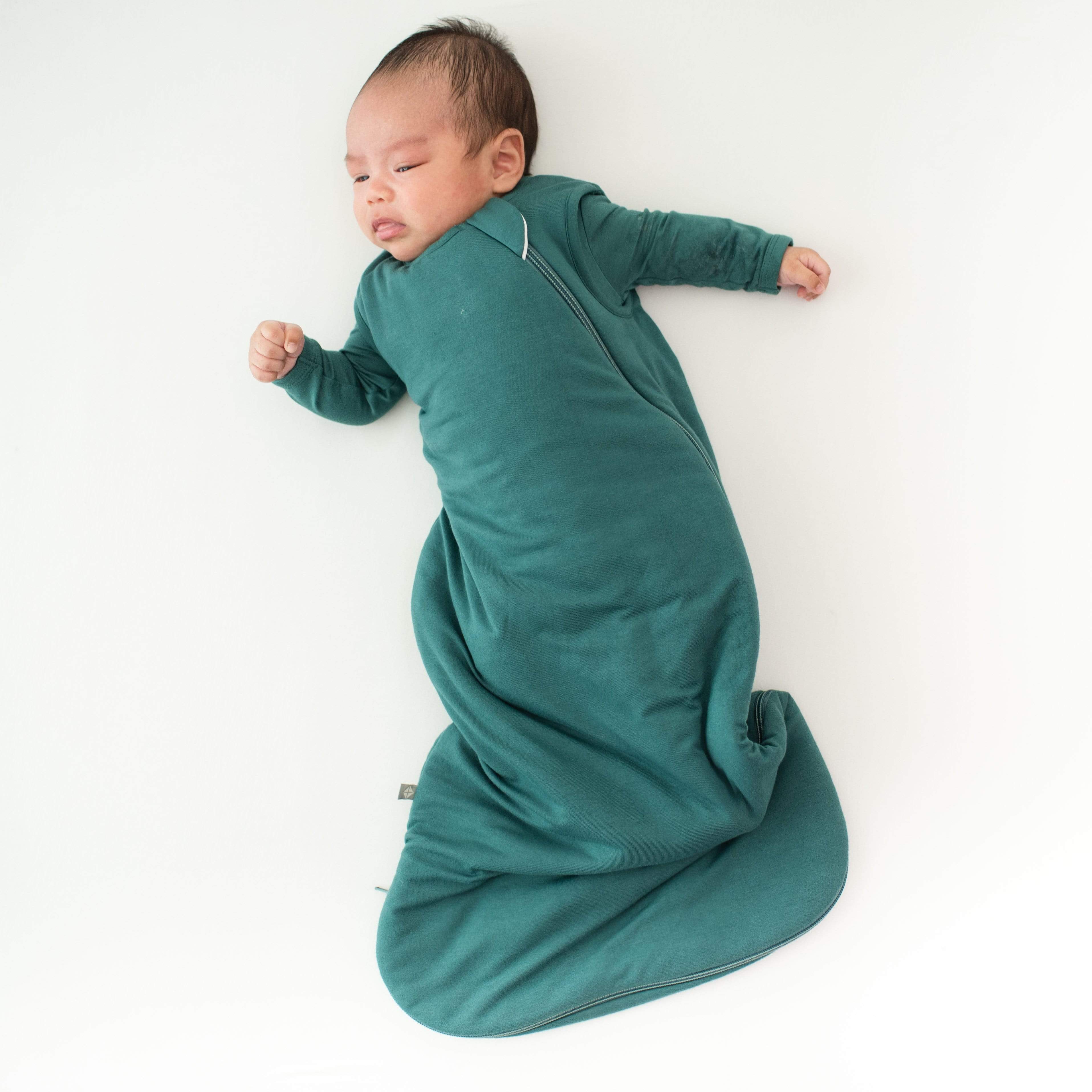 Infant wearing Kyte Baby Sleep Bag TOG 2.5 in Emerald green with matching long sleeve bodysuit underneath