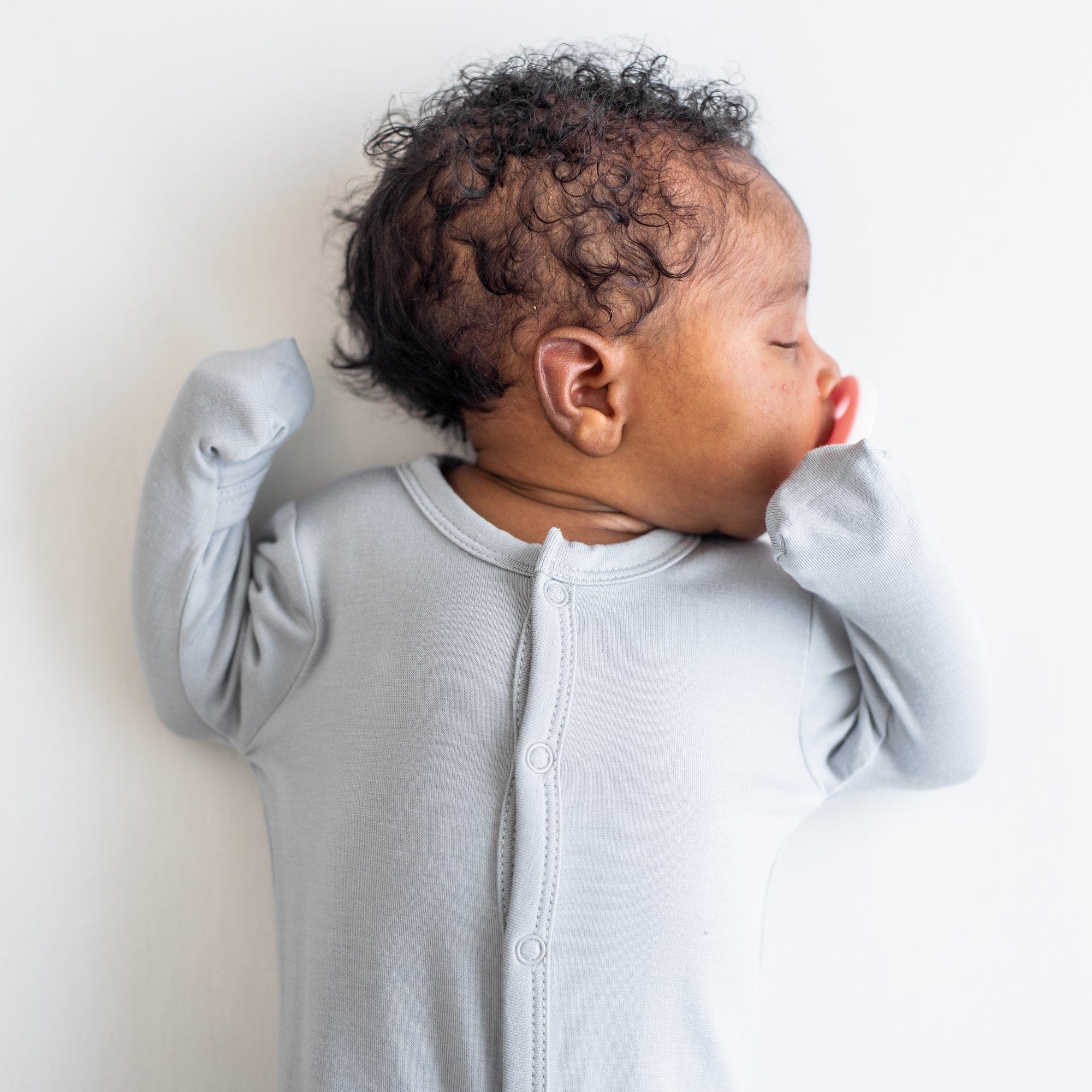 Sleeping infant wearing Kyte Baby Footie in Storm with fold-over cuffs