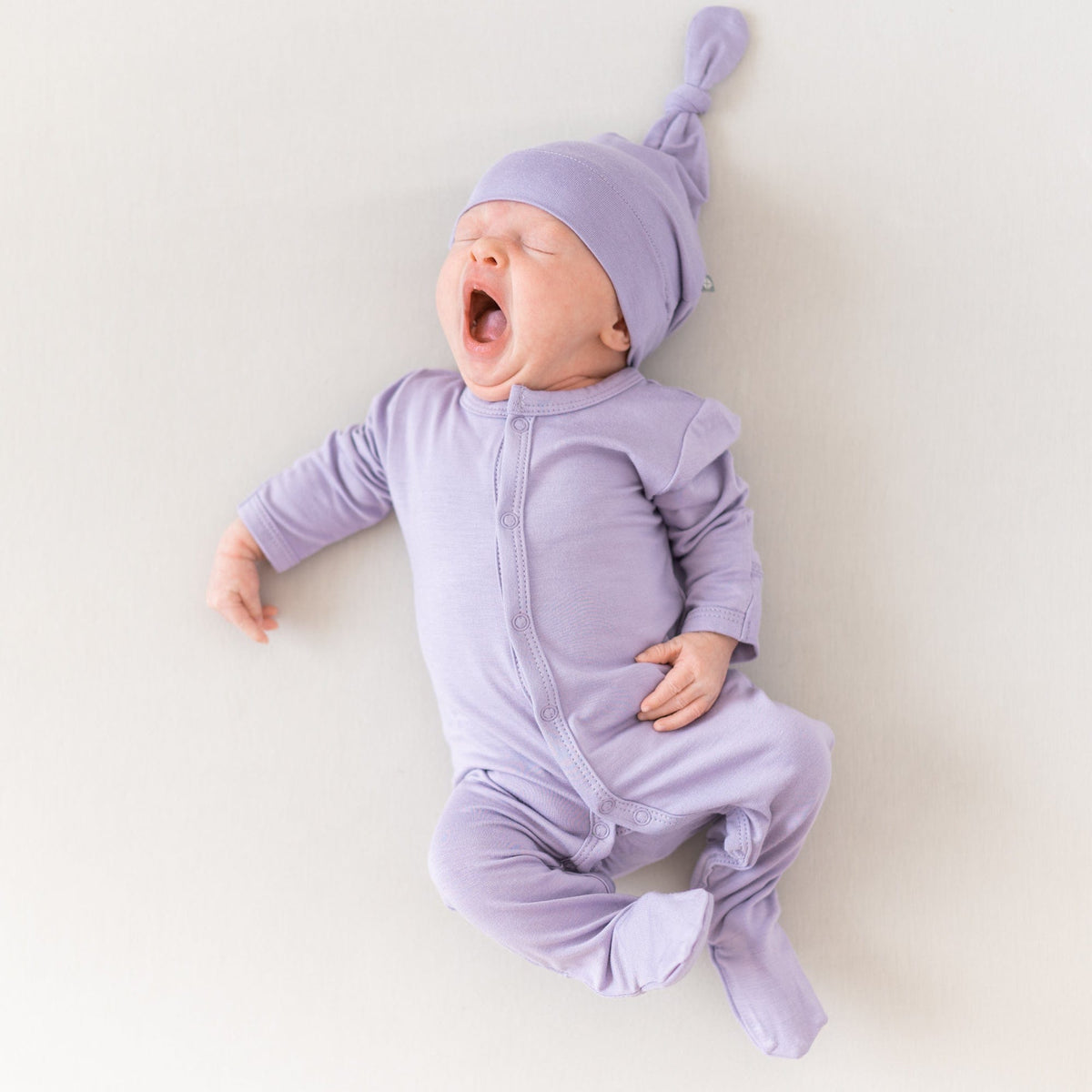 Newborn wearing Kyte Baby Footie in Taro