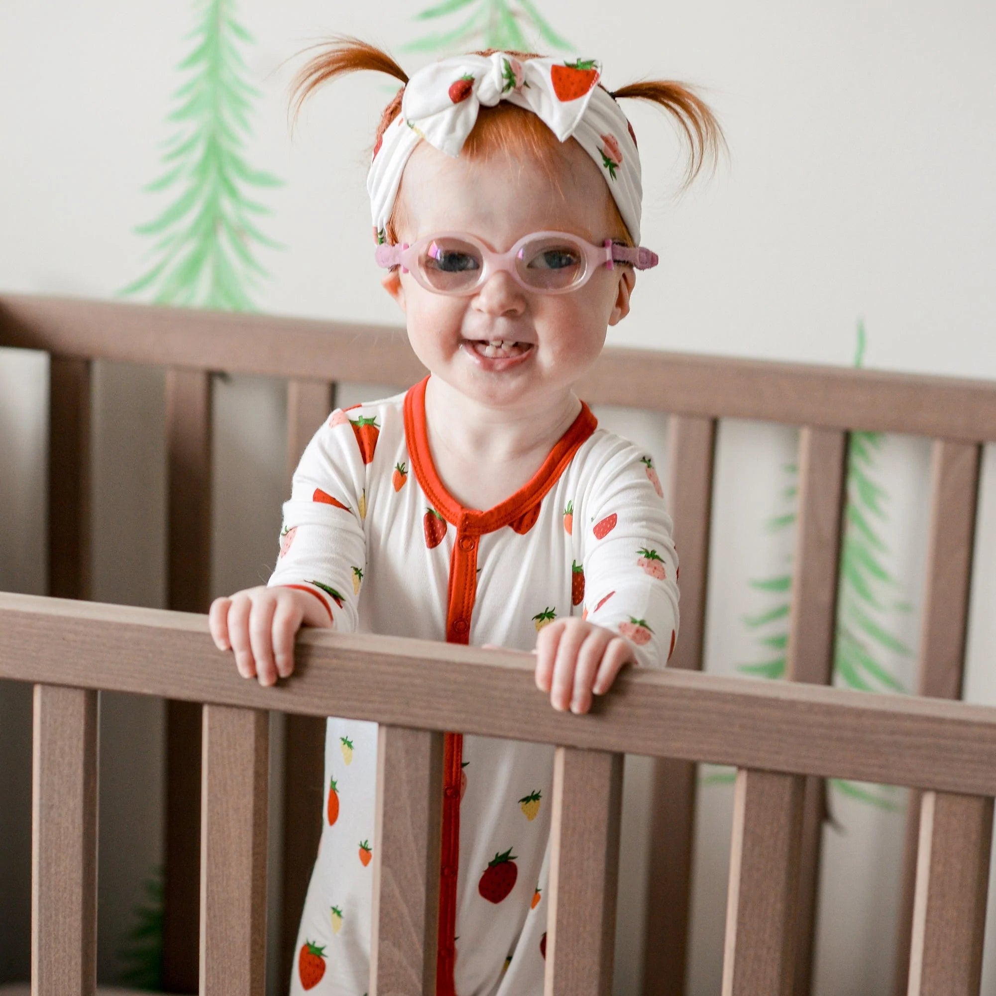 Child wearing long sleeve Kyte Baby Romper with snaps in Strawberry