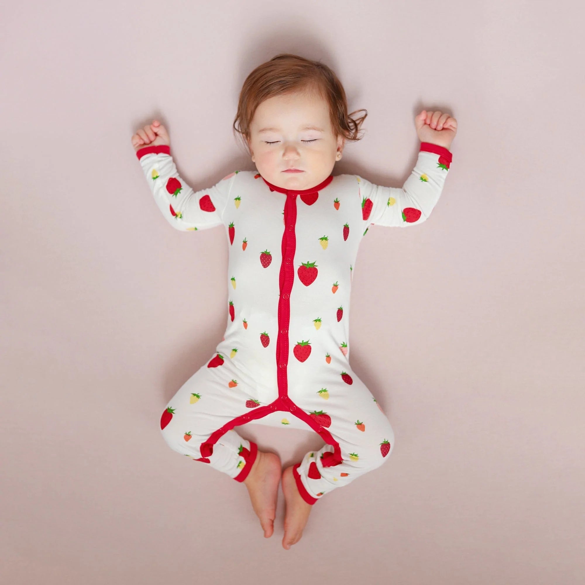 Infant wearing Kyte Baby Romper in Strawberry