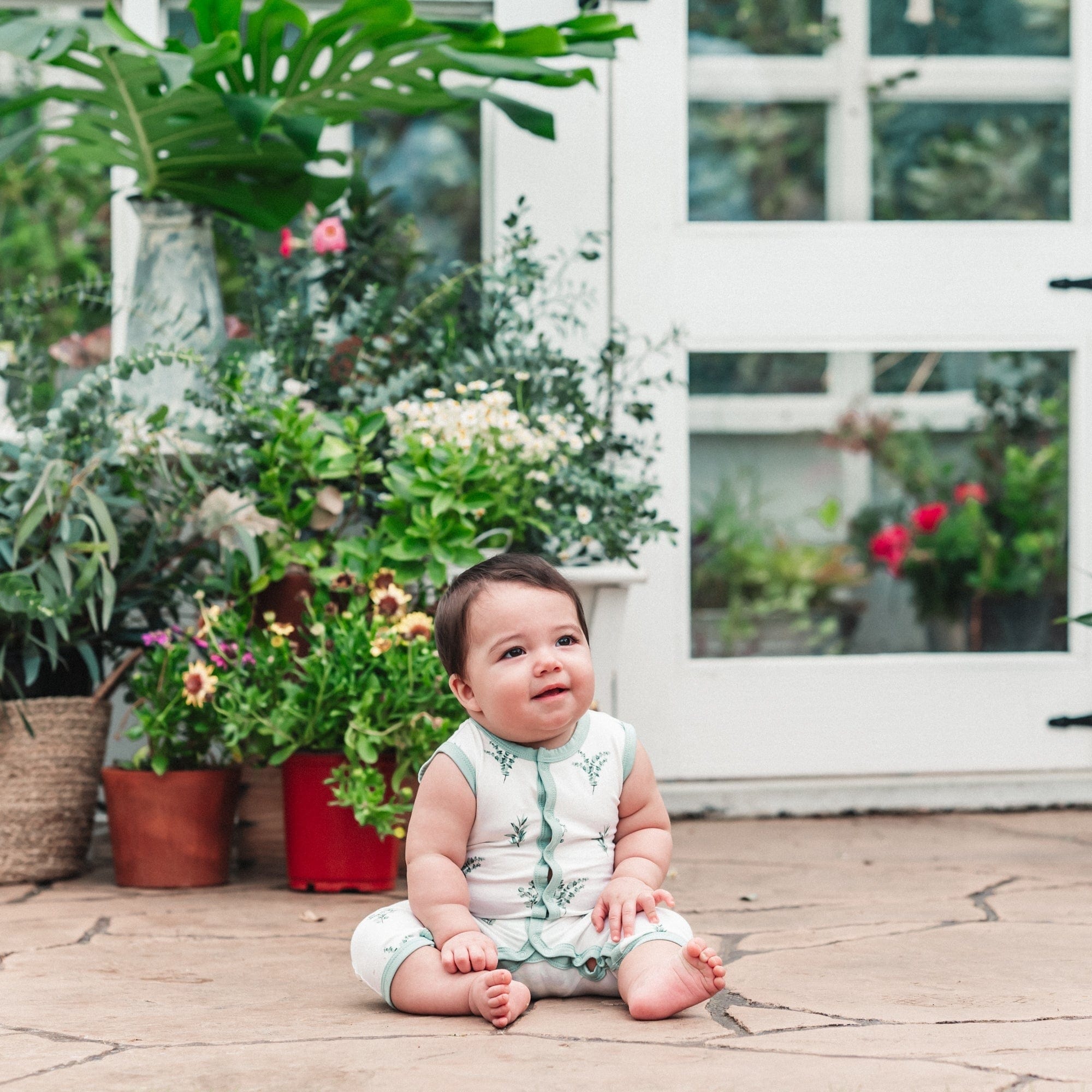 Baby wearing Kyte Baby Sleeveless capri Romper in Eucalyptus