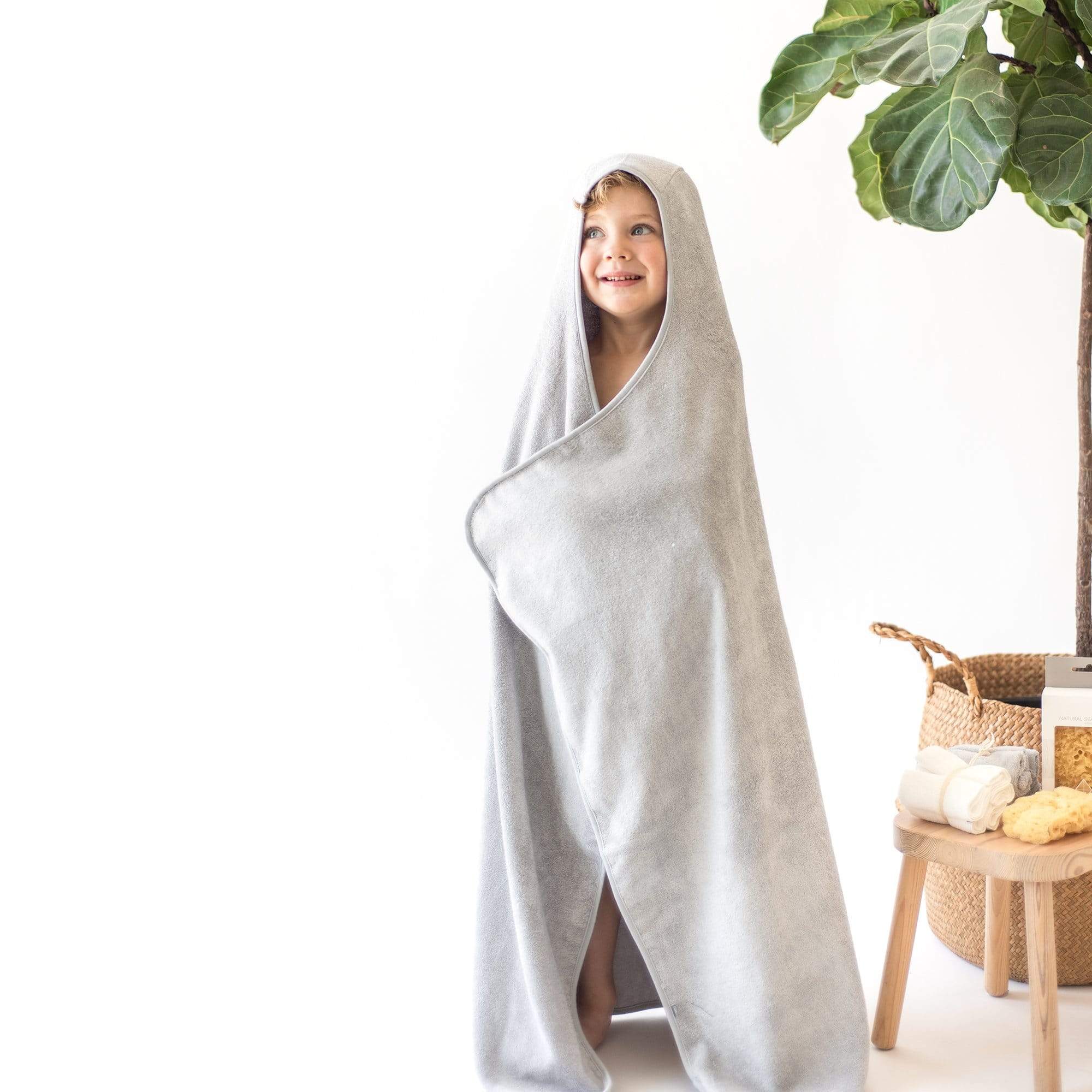 Toddler wrapped in Kyte Baby Hooded Bath Towel in Storm