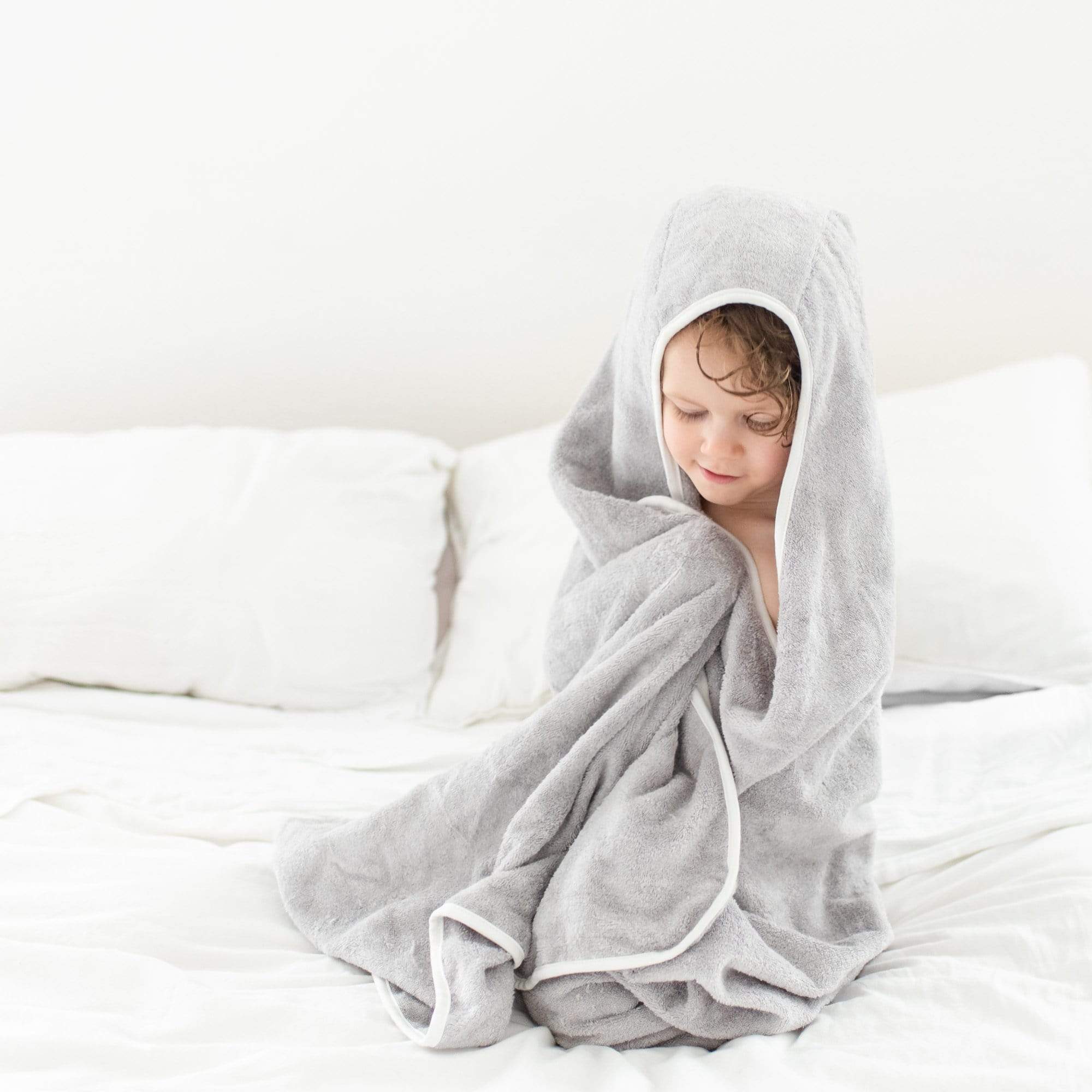 Child wrapped in Kyte Baby Toddler Hooded Bath Towel in Storm with Cloud Trim