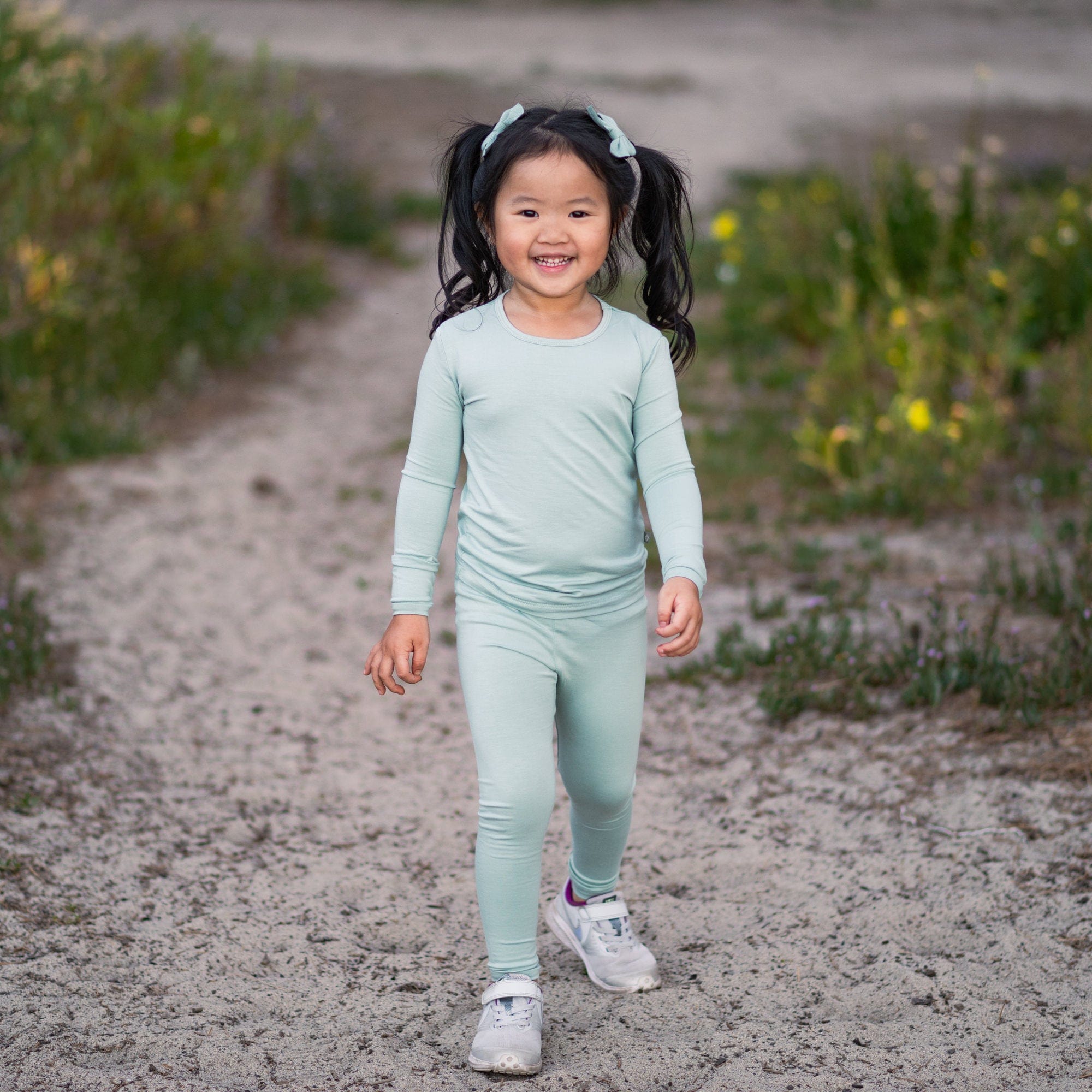 Little girl standing on a dirty path and wearing a Long Sleeve Pajama Set in Sage