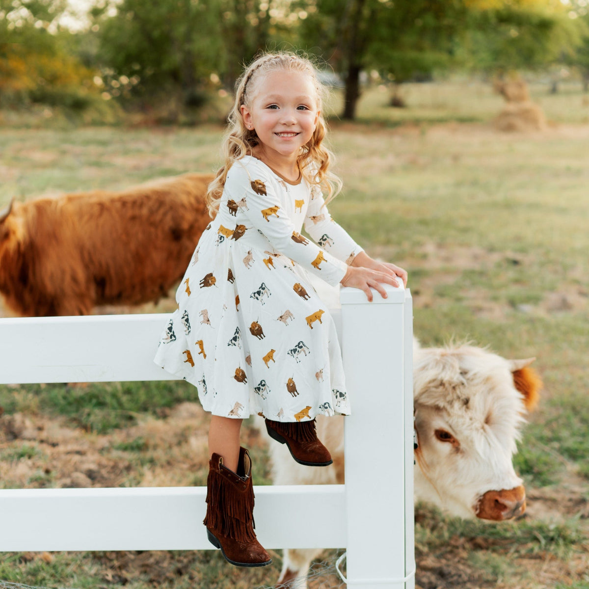 Girl wearing Kyte Baby Long Sleeve Twirl Dress in Moo cow print