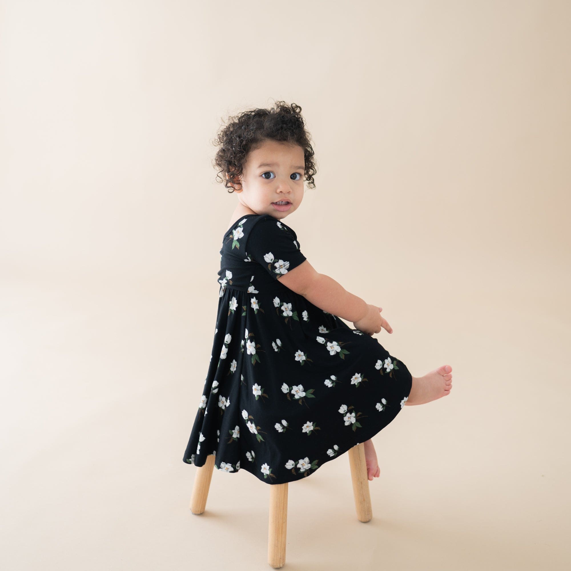 Girl wearing Kyte Baby Twirl Dress in Small Magnolia on Midnight