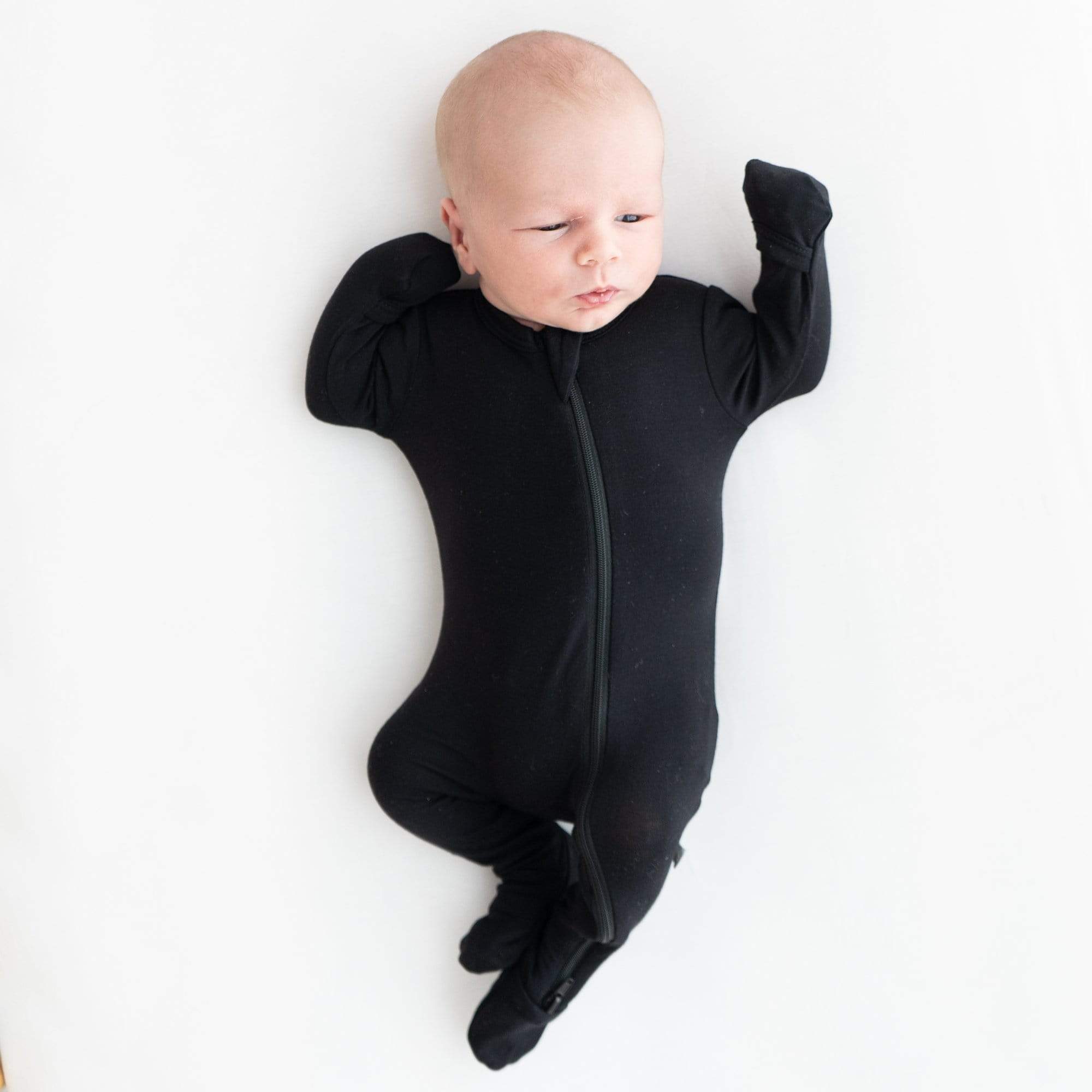 Baby wearing Kyte Baby breathable bamboo Zippered Footie pajamas in Midnight black