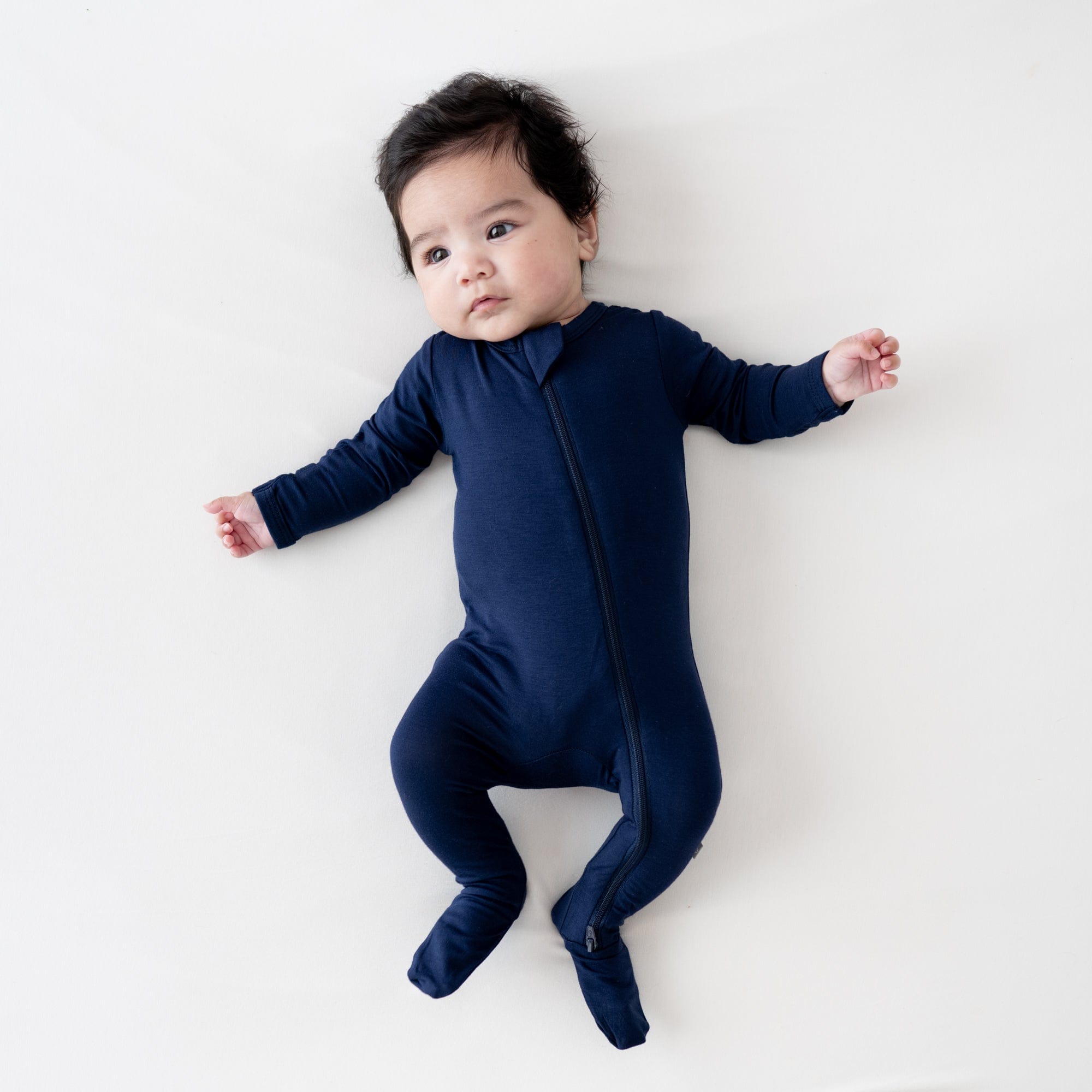 Baby wearing Kyte Baby Zippered Footie in Navy