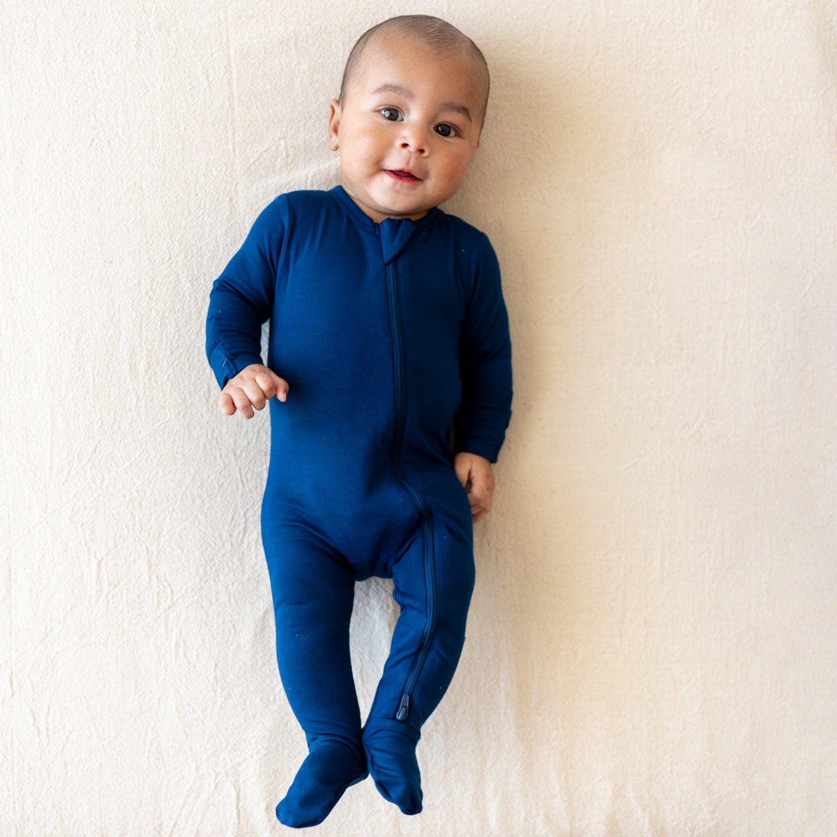 Infant looking into the camera wearing Zippered Footie in Tahoe