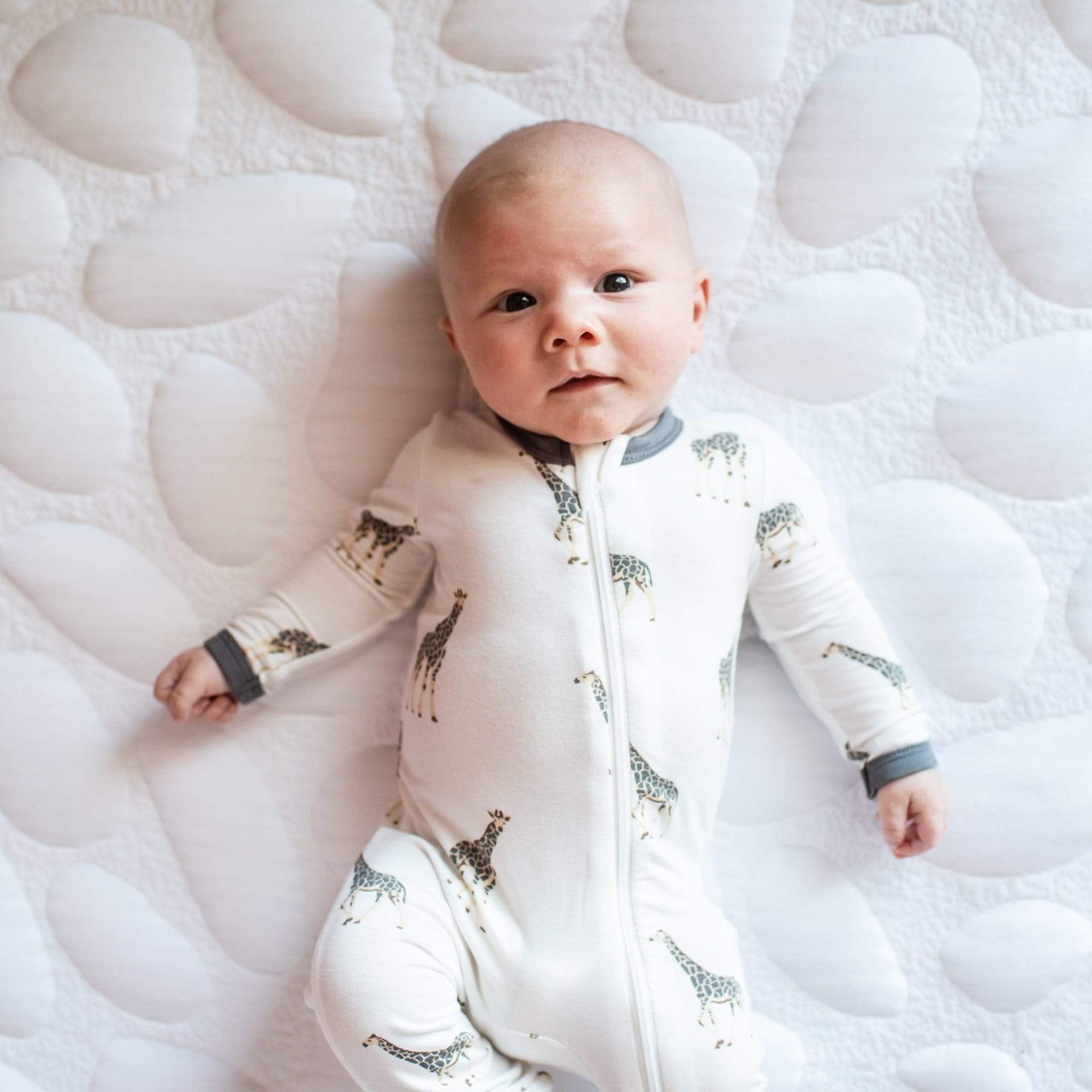 Newborn wearing Kyte Baby Bamboo Zippered Romper in Giraffe