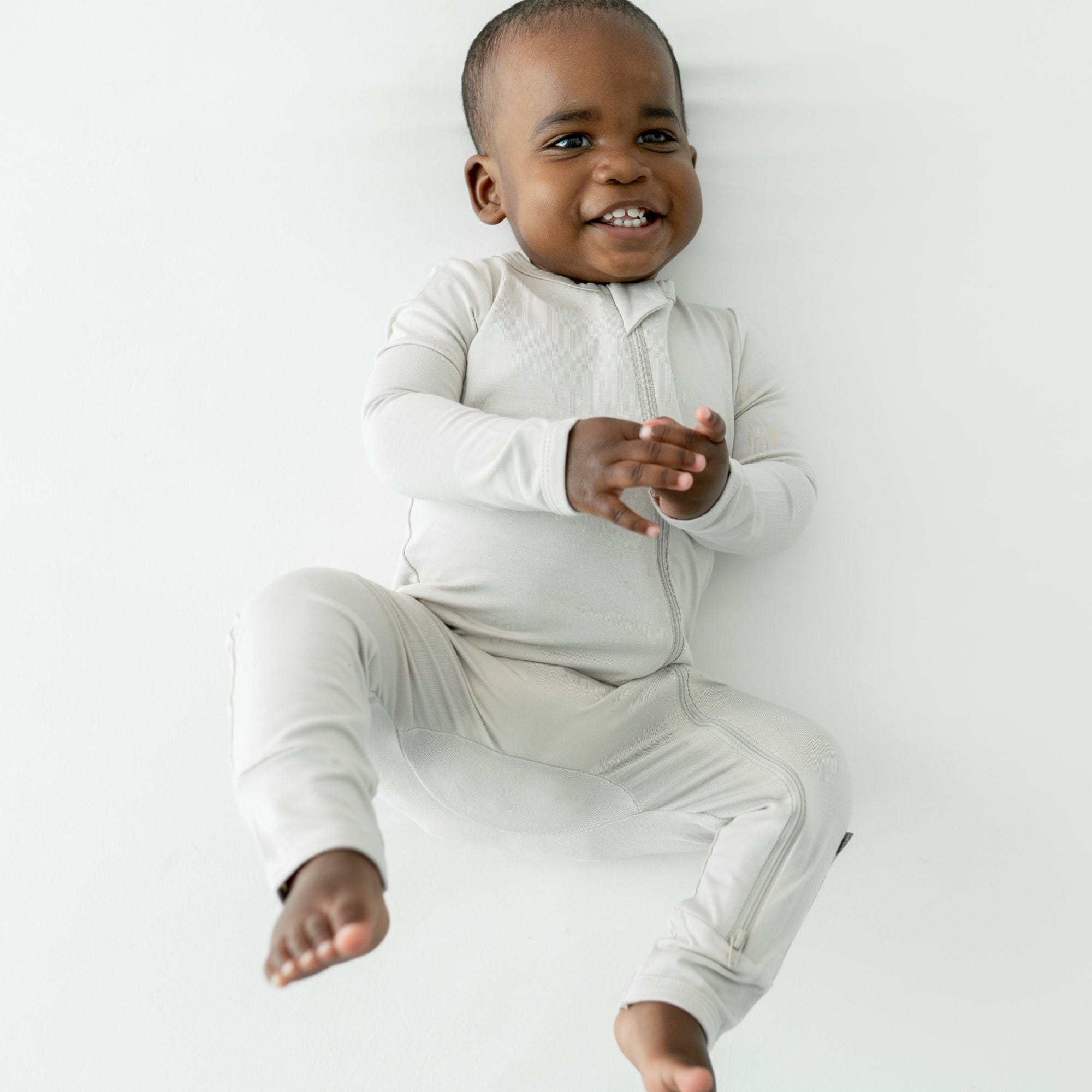 Smiling baby wearing a Zippered Romper in Oat