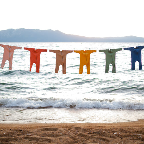 a rainbow of kyte baby rompers hanging in lake tahoe