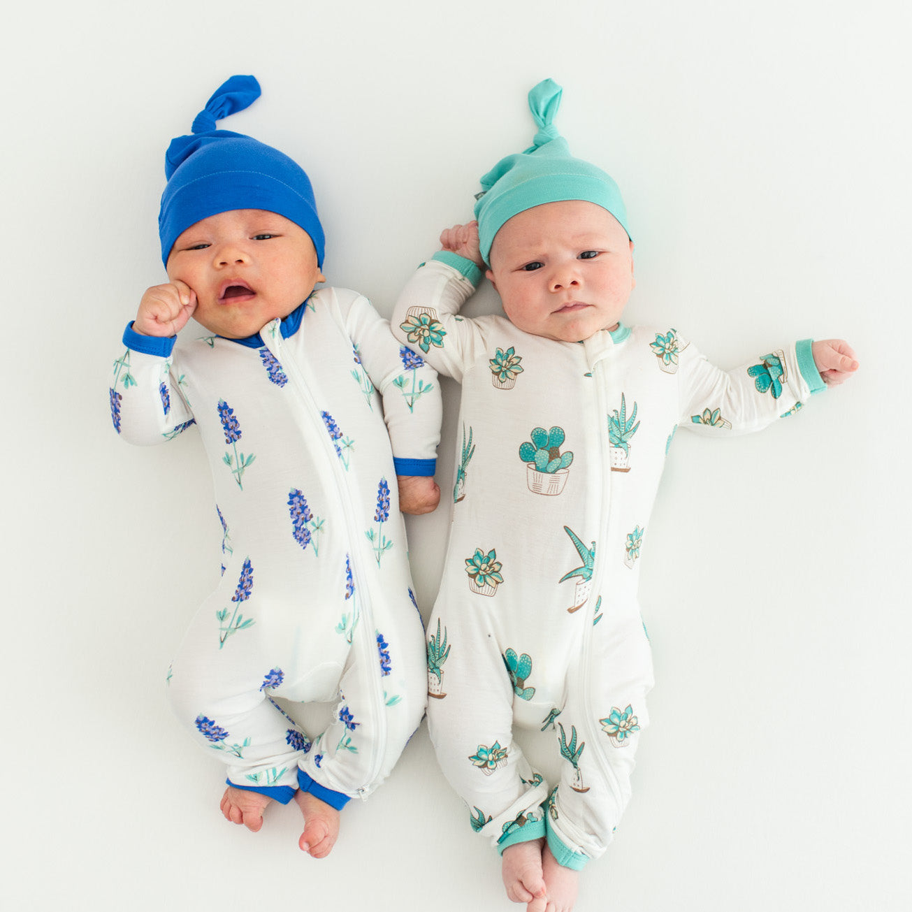 Asian and caucasian baby laying on back in bluebonnet print and succulent print pajamas