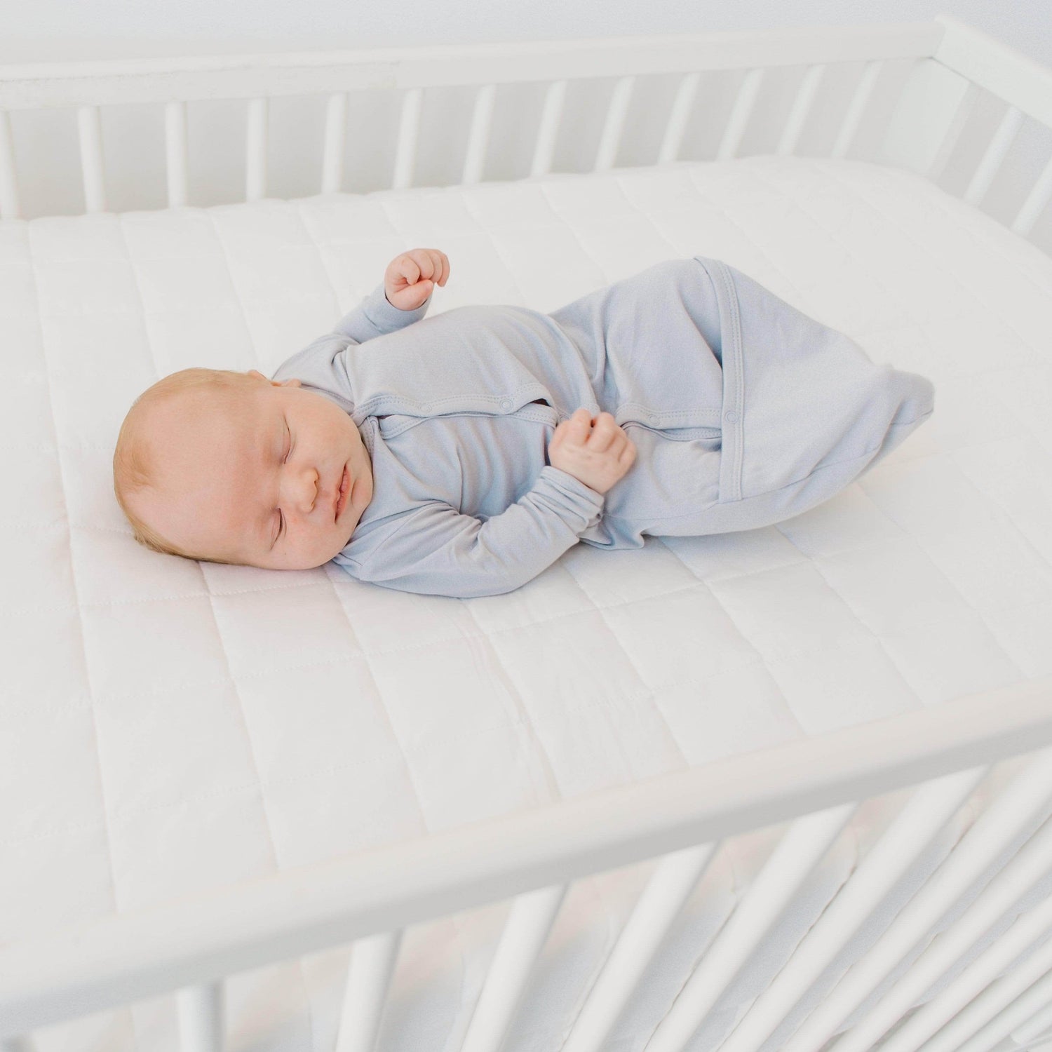 Newborn sleeping in blue swaddler pajamas