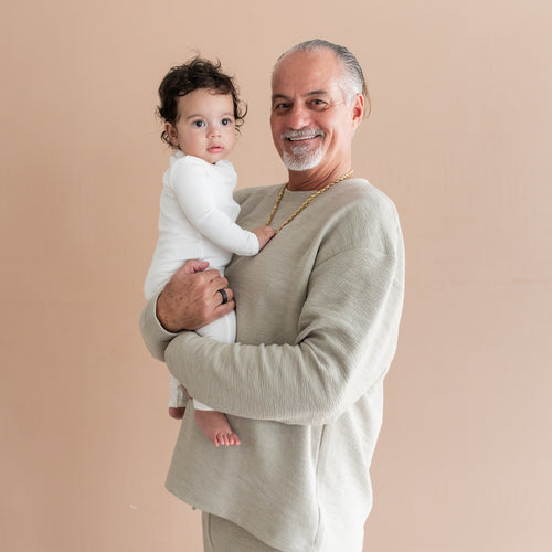 Grandfather holding infant wearing loungewear from Kyte Baby