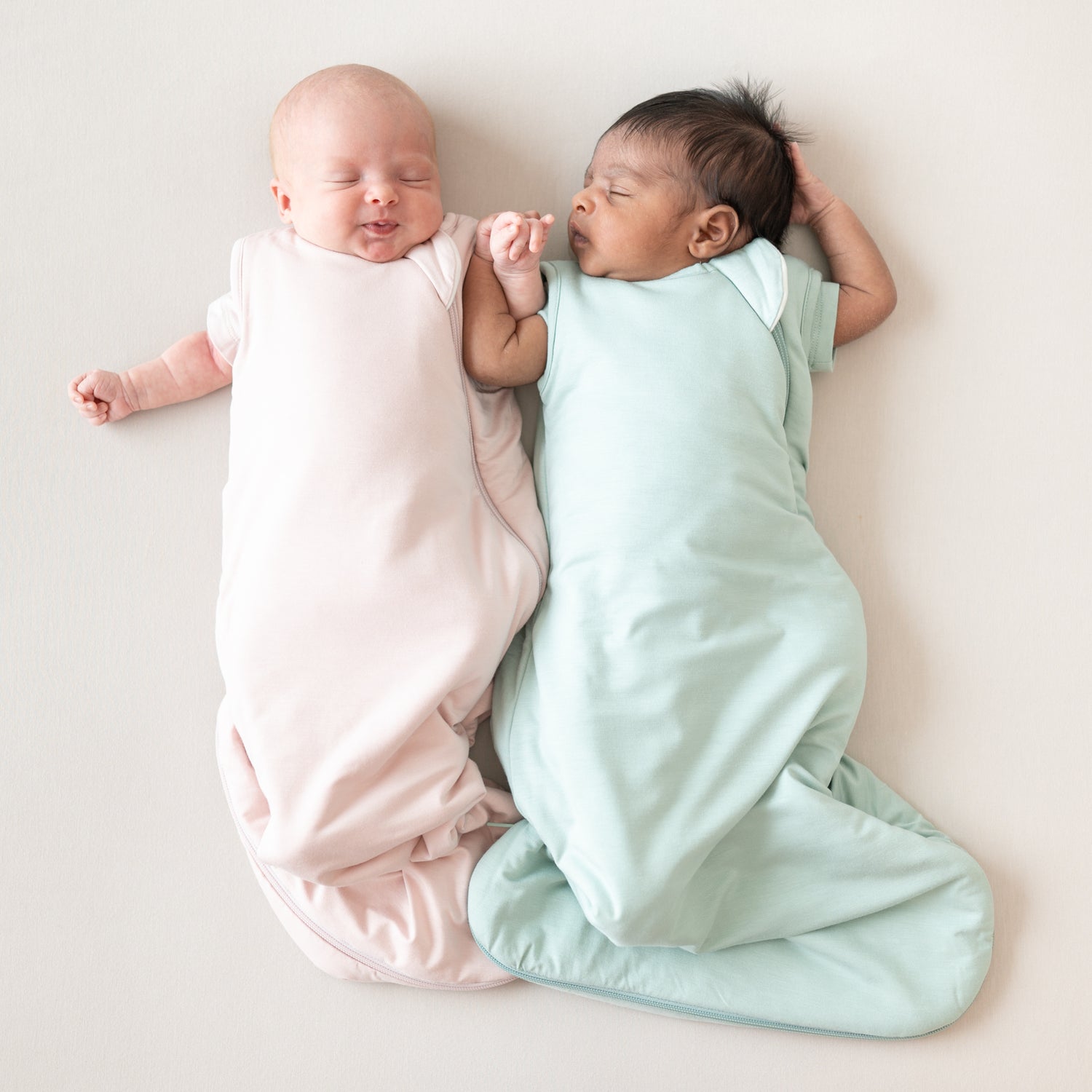 two babies sleeping next to each other in xs kyte baby sleep bags
