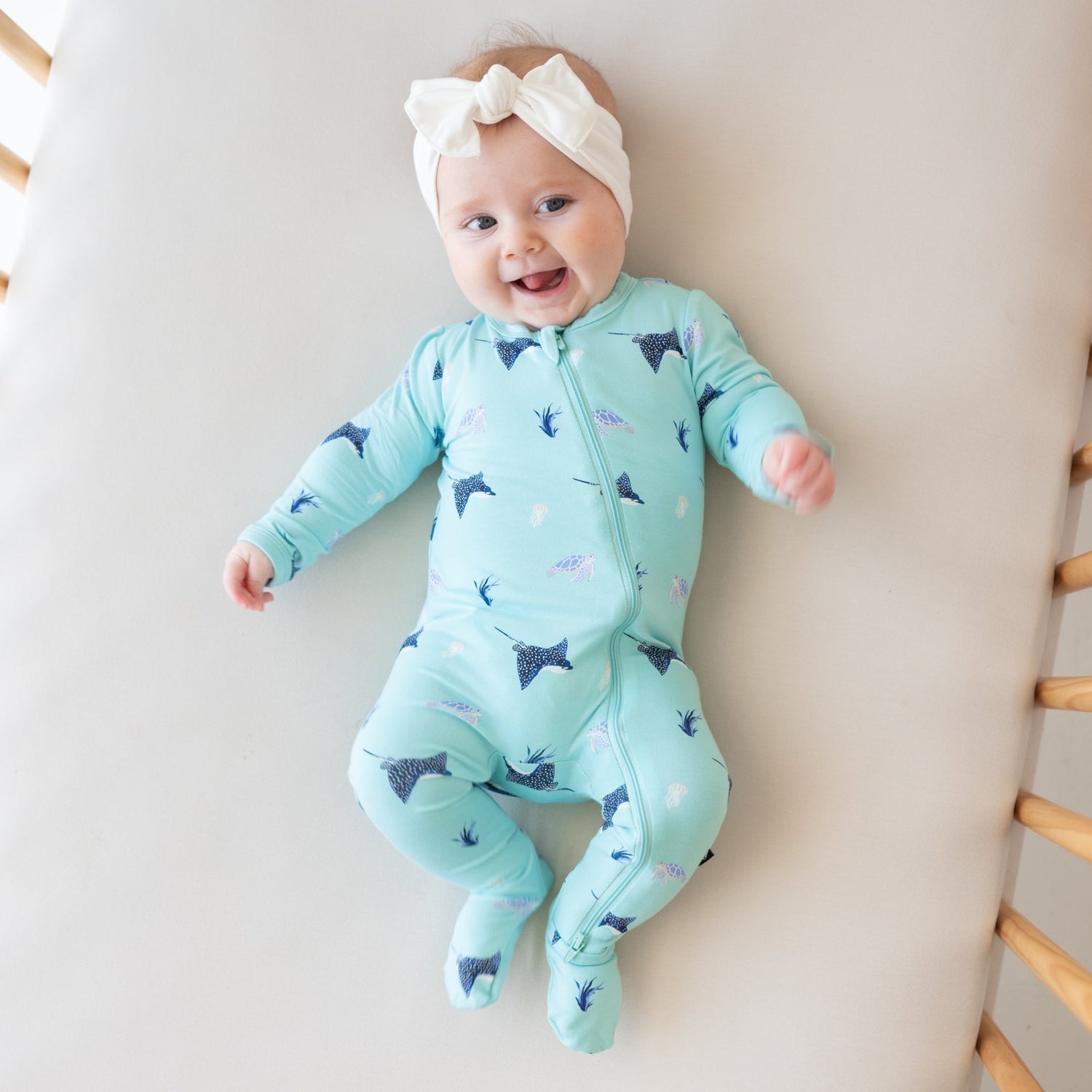 Infant wearing Kyte Baby Zippered Footie in Eagle Ray print