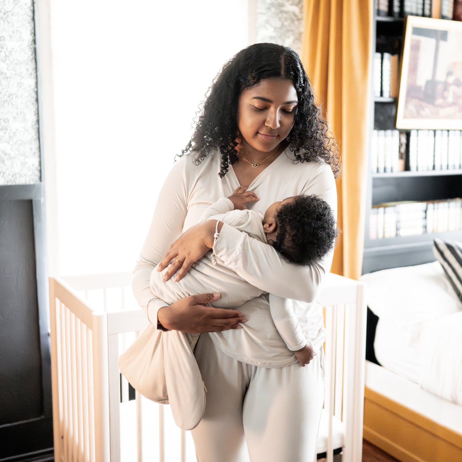 mom holding sleeping baby in oat sleep bag