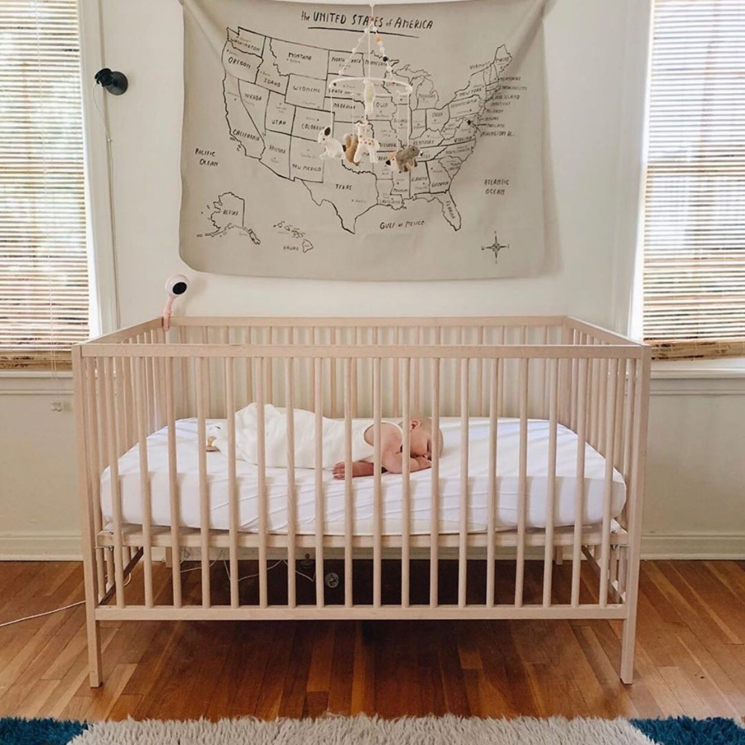 Baby sleeping in crib wearing a white sleep bag