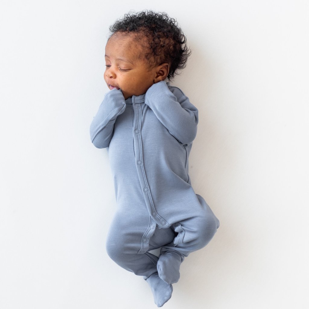 Baby laying and sleeping in blue footie pajama