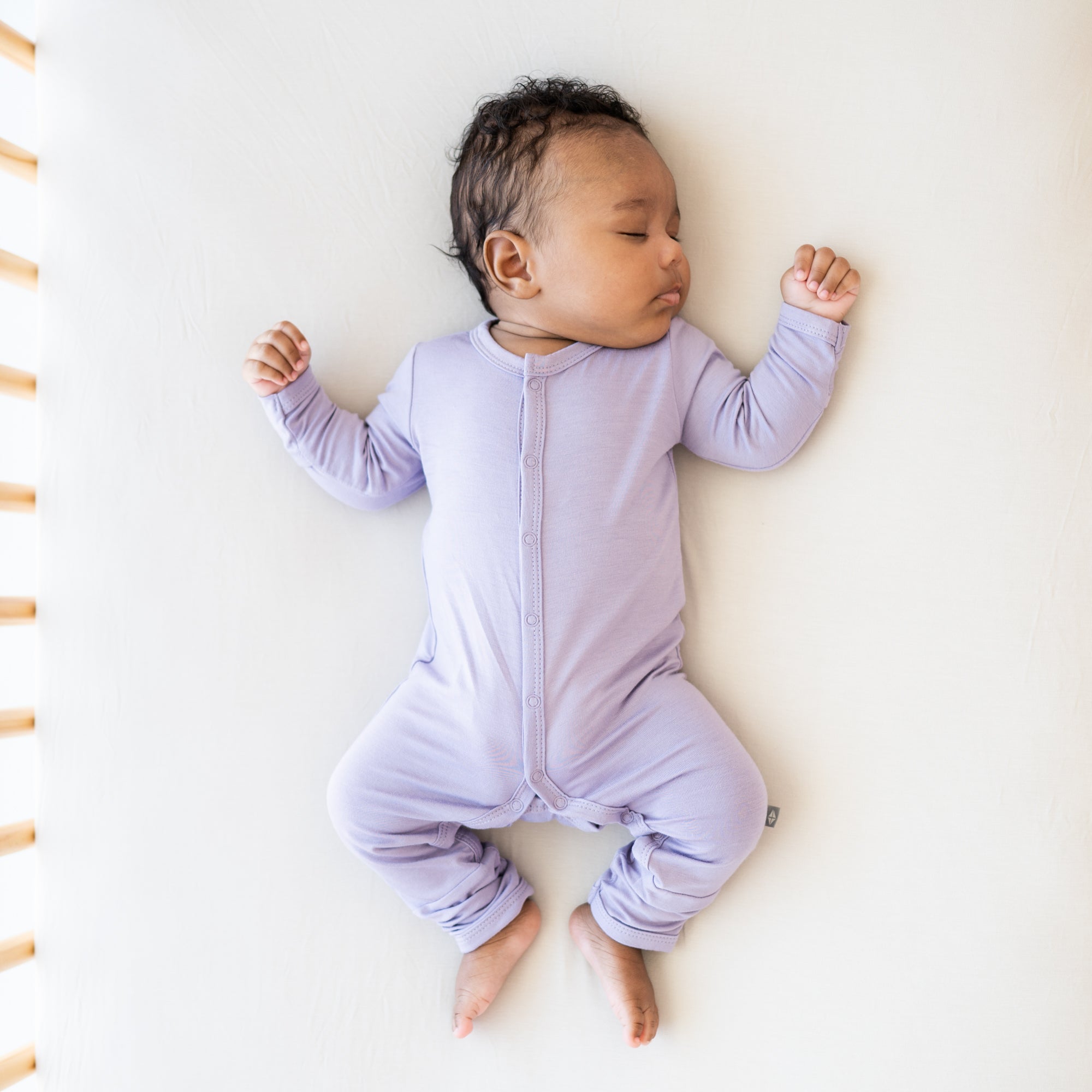 Infant sleeping in purple snap romper pjs