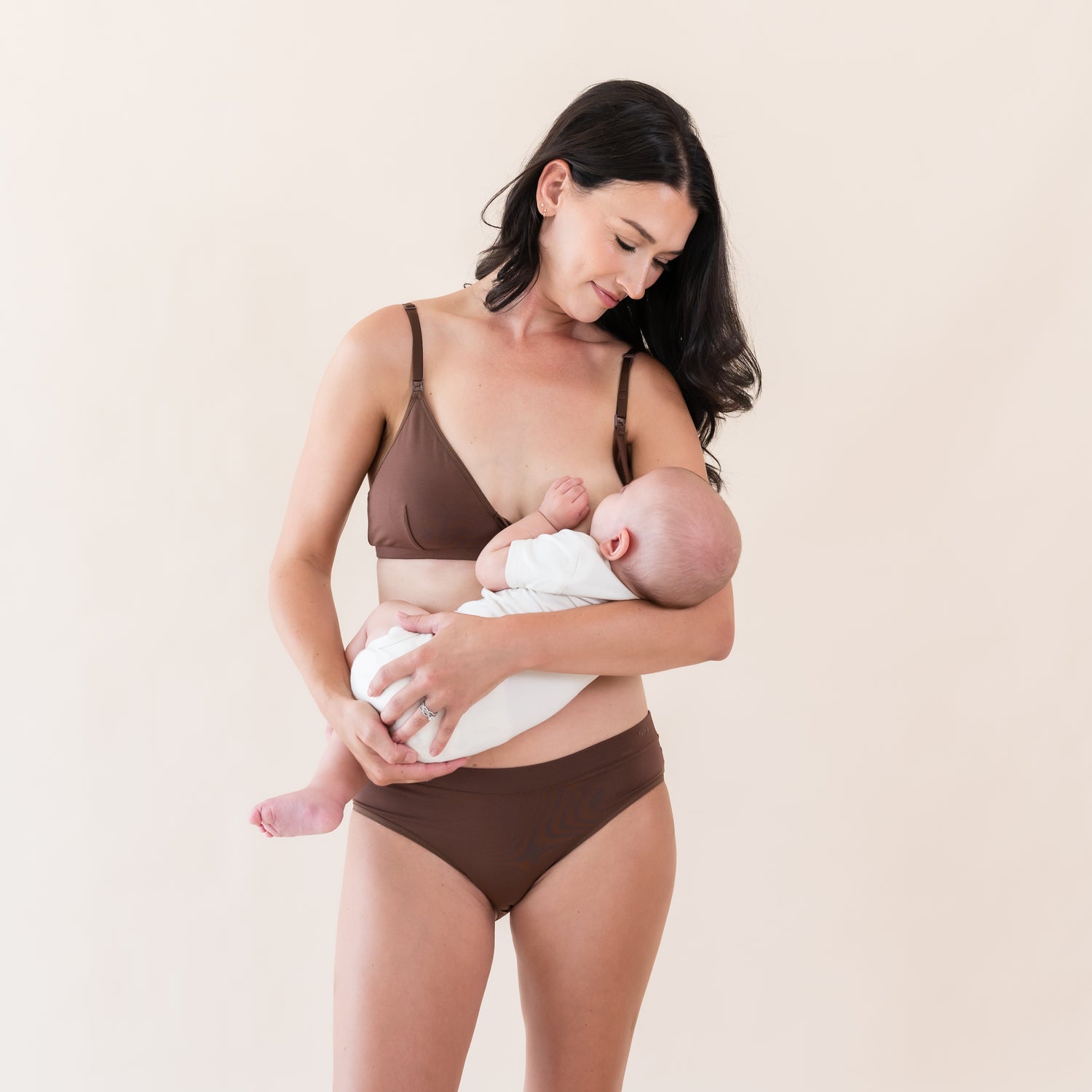 Woman wearing Kyte Baby Nursing Bra and feeding her infant