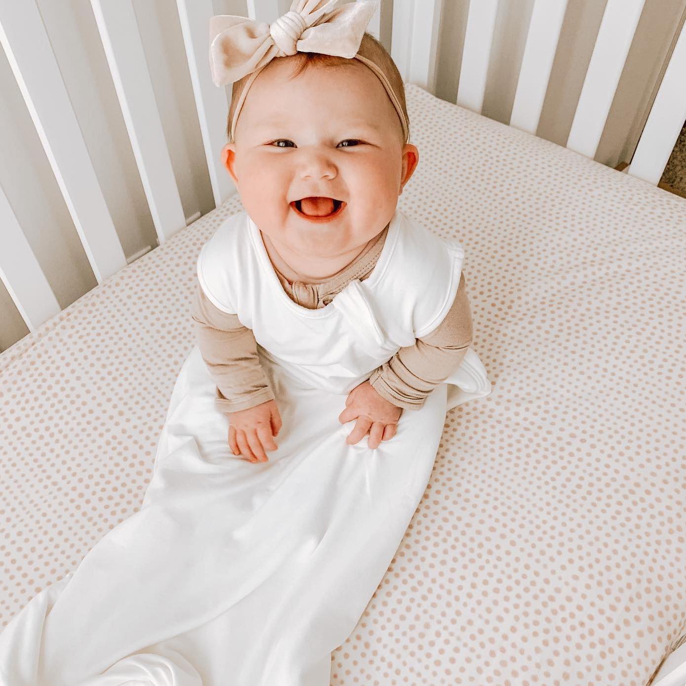 baby smiling in crib and wearing a kyte baby sleep bag