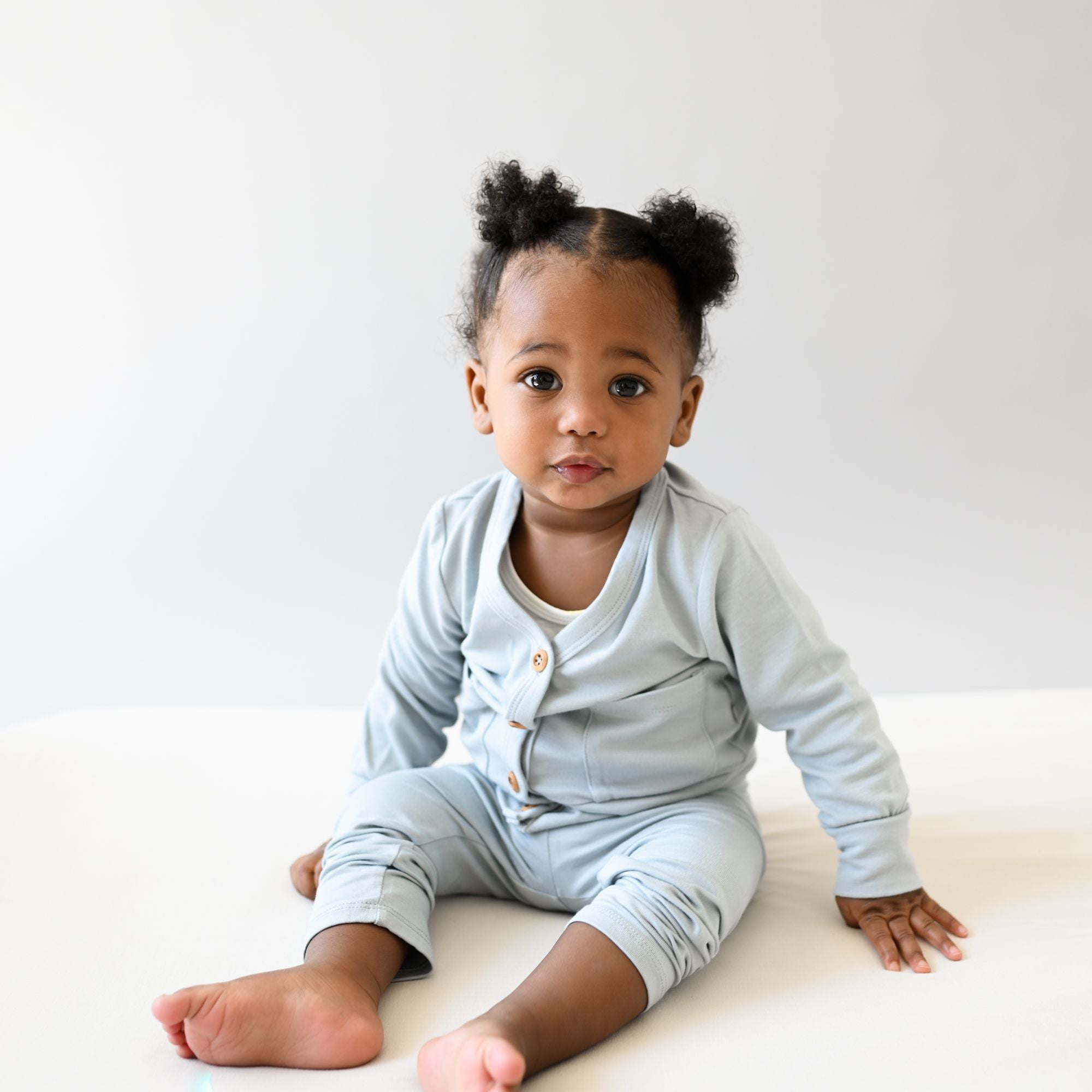 Baby sitting wearing bamboo jersey cardigan in the color fog