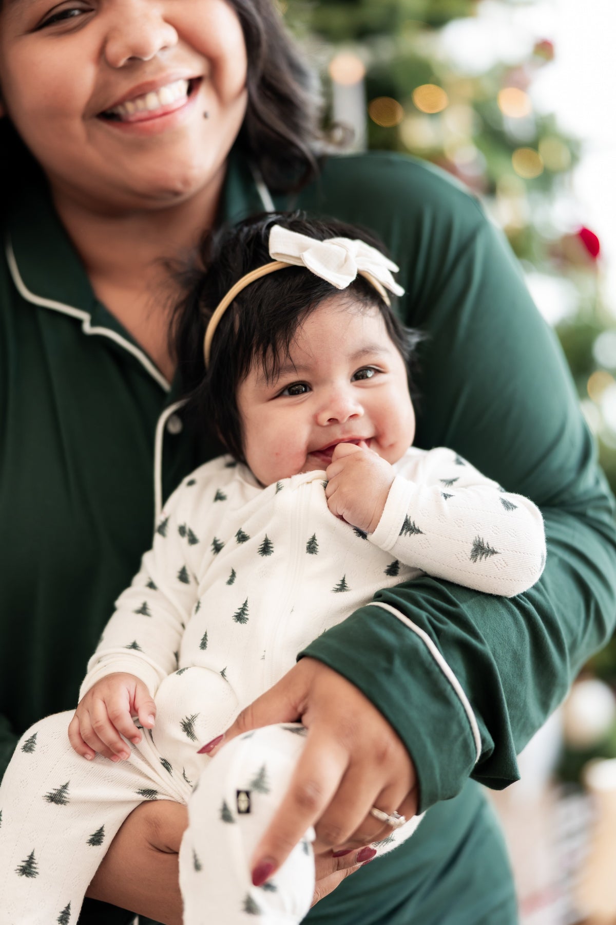 Mommy smiling in long sleeve pajama set in cypress holding her Baby wearing Pointelle Zippered Footie in Christmas Trees