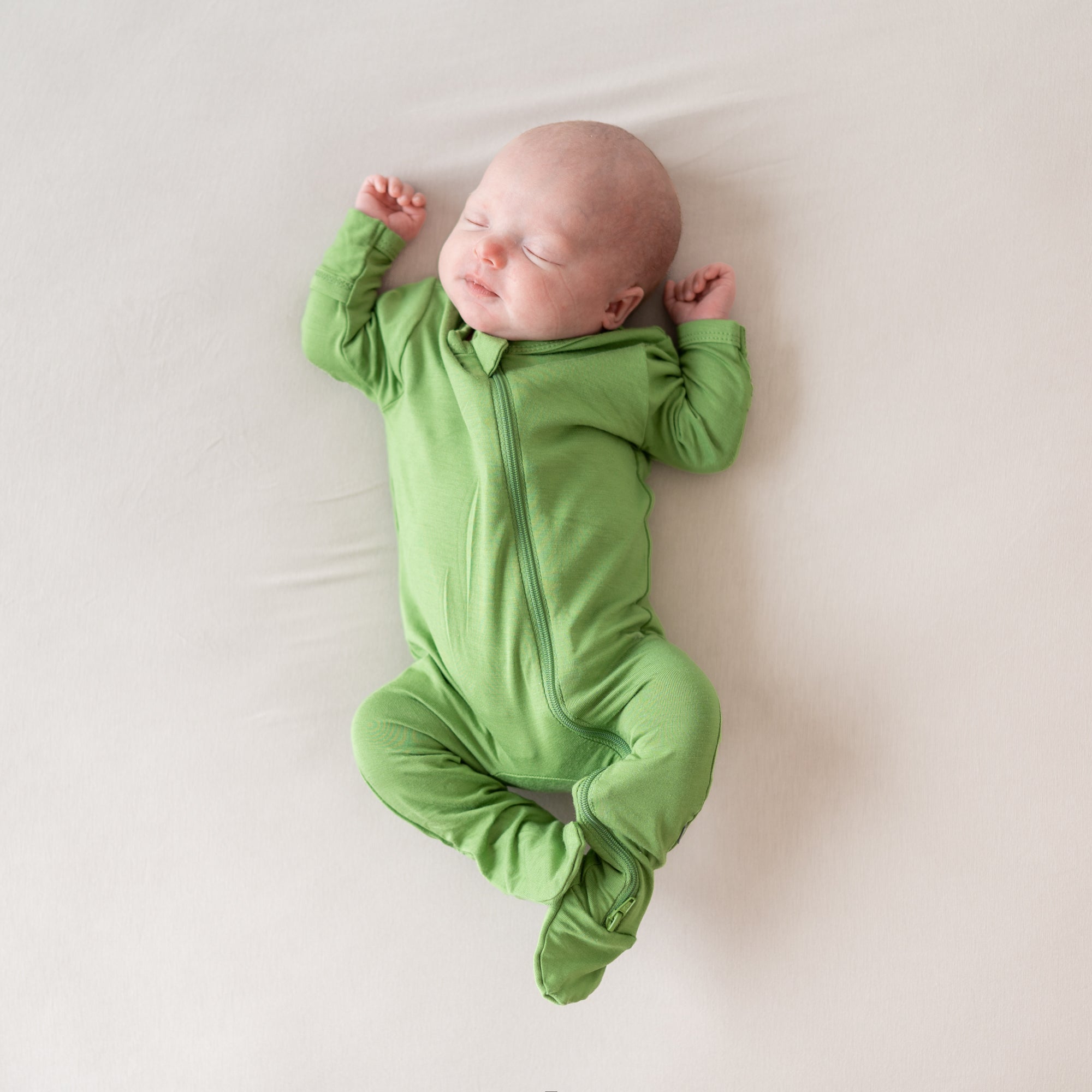 Baby modelling zippered footie in palm