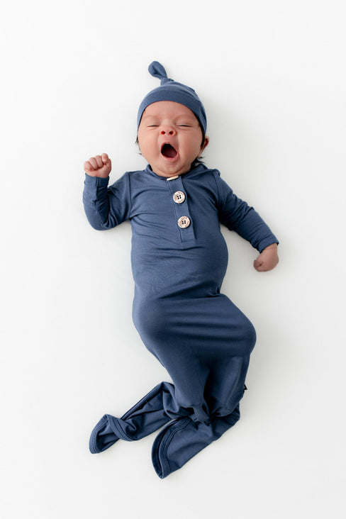 Baby yawning wearing a knotted gown and hat in oxford.