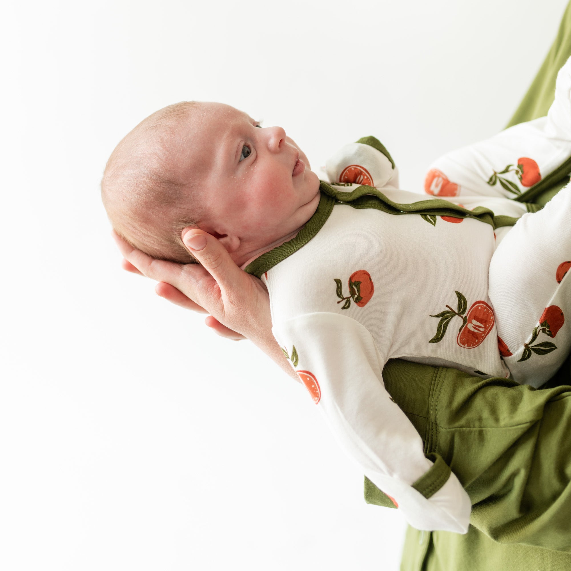 Baby Being Held by their parent wearing persimmon snap footie