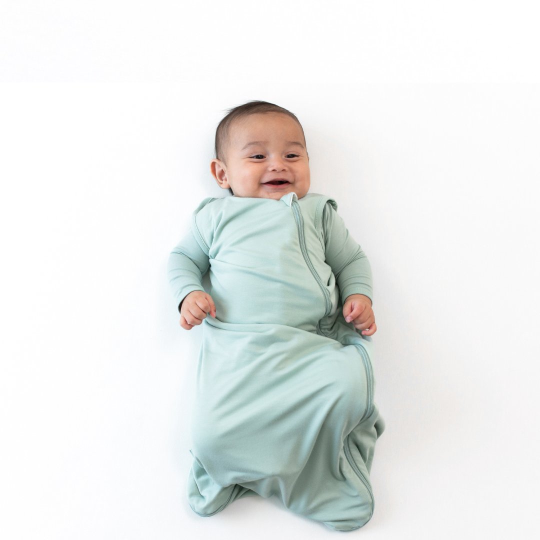 Three babies laying down wearing sleep bags in colors storm, sage and slate