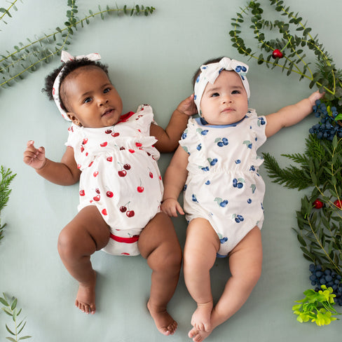 Babies wearing bamboo Kyte Baby Bubble Rompers in Cherry and Blueberry