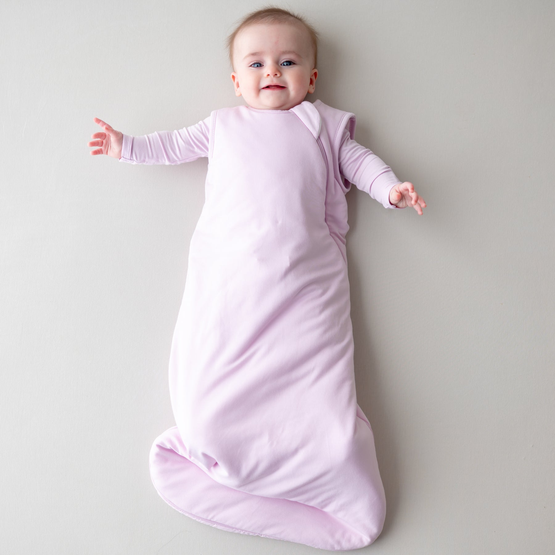 Baby wearing a 1.0 tog sleep bag in a light purple color