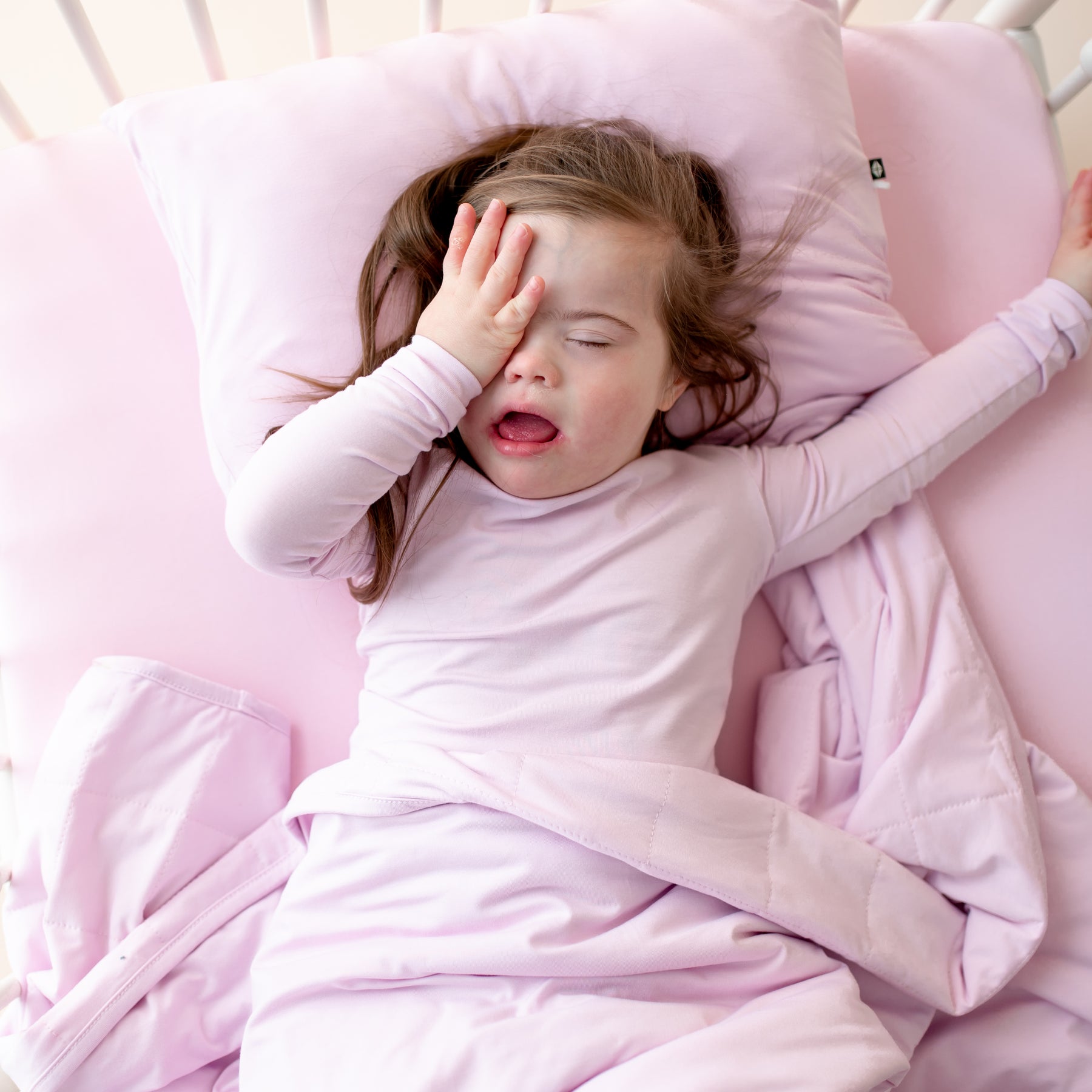 Child sleeping in a purple toddler bed with a purple blanket