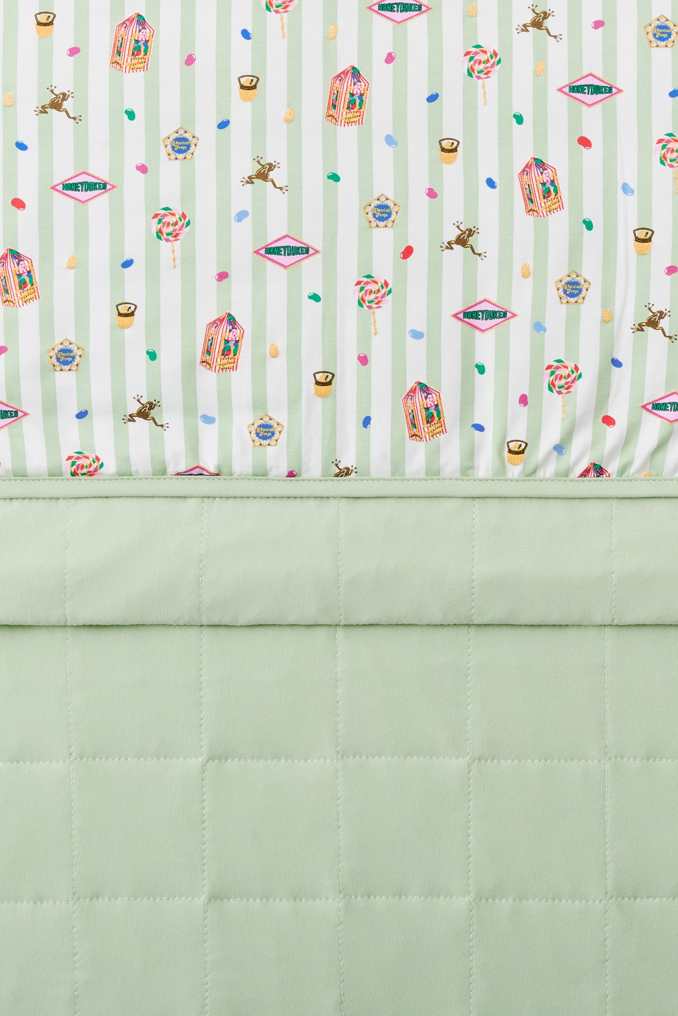 Baby blanket with colorful Harry Potter patterns print on a green and white striped fabric with light green fabric at the back.