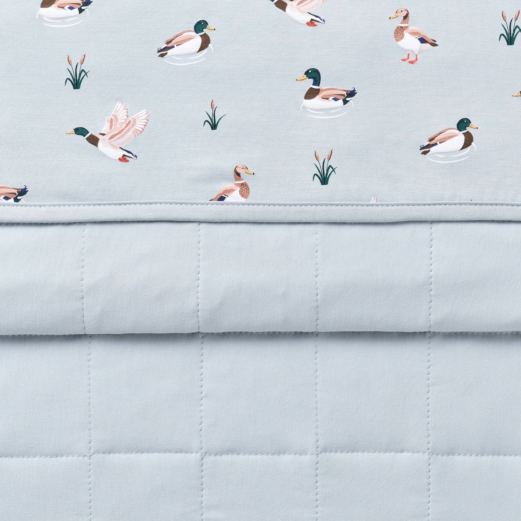 Close up of the Baby Blanket in Mallard Duck showing the quilted blue backing and patterned smooth top layer