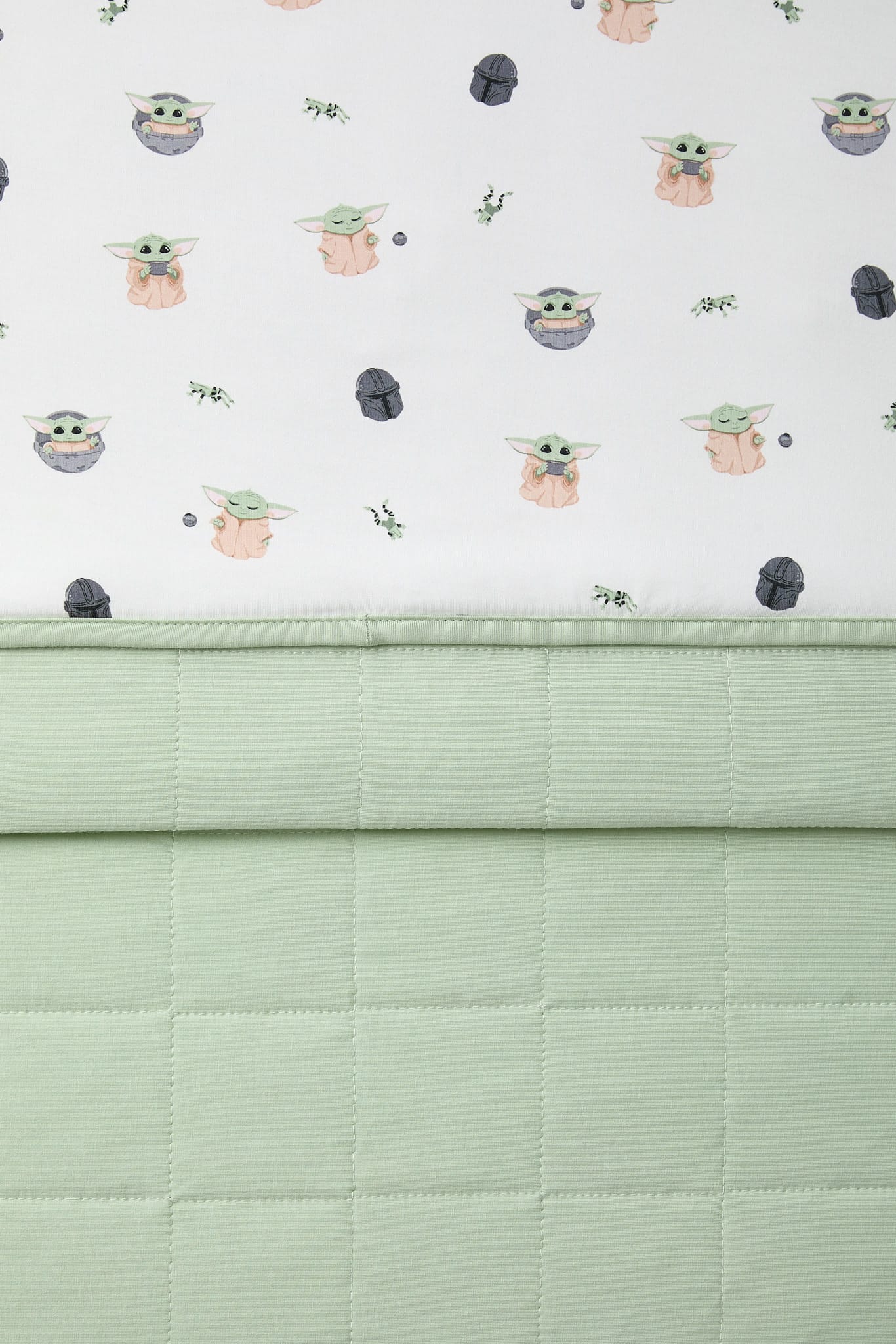 Close up of the Baby Blanket in Grogu™ showing the light green quilted backing and smooth printed top layer
