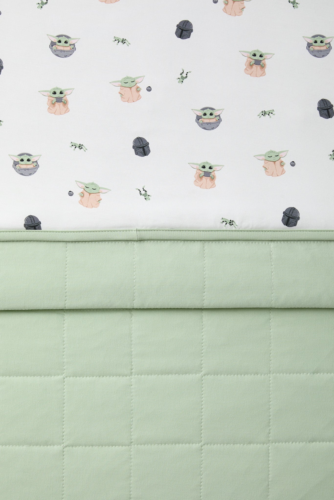 Close up of the Baby Blanket in Grogu™ showing the light green quilted backing and smooth printed top layer