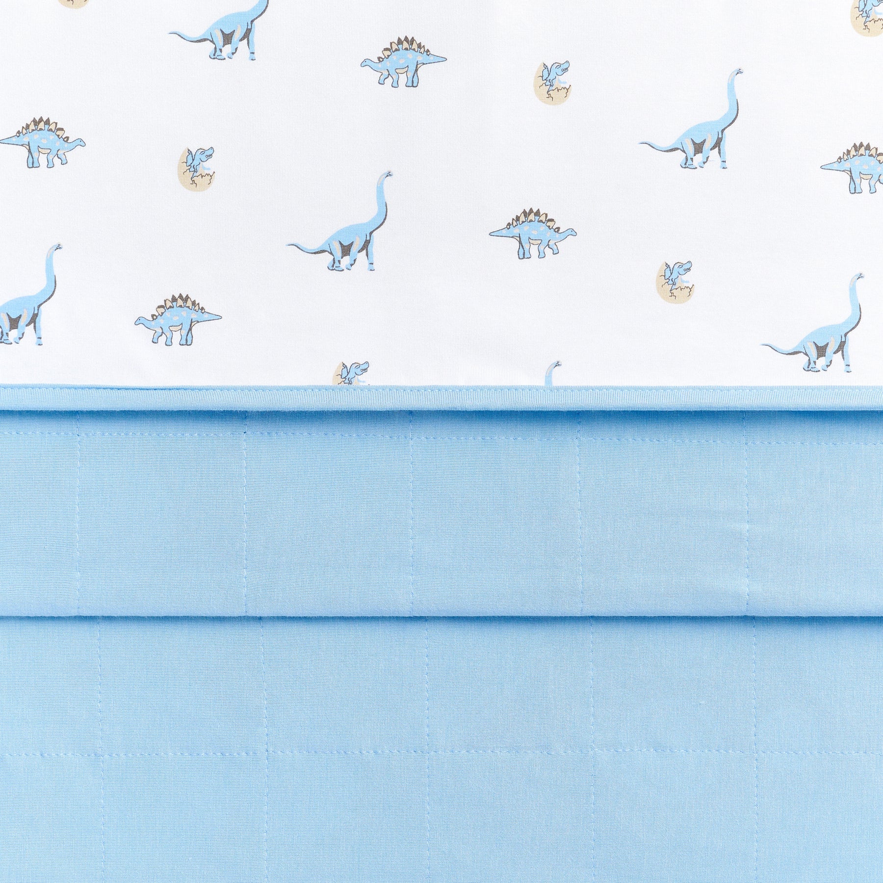 Close up of the Toddler Blanket in Jurassic 1.0 showing the baby blue quilted backing and dinosaur printed smooth top layer