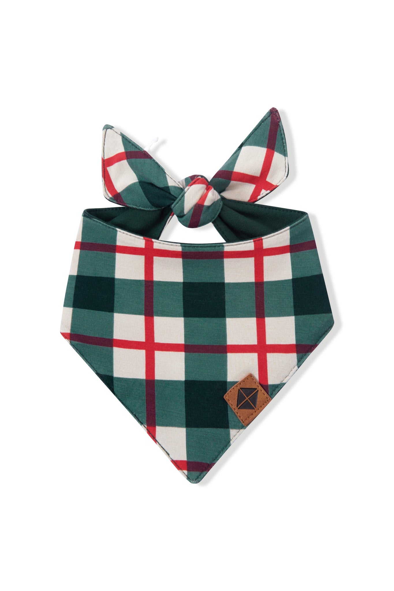 A dog bandana bib with a green, white, and red plaid pattern, featuring a tie at the top and a small brown leather patch on the bottom right corner, shown on a plain white background.